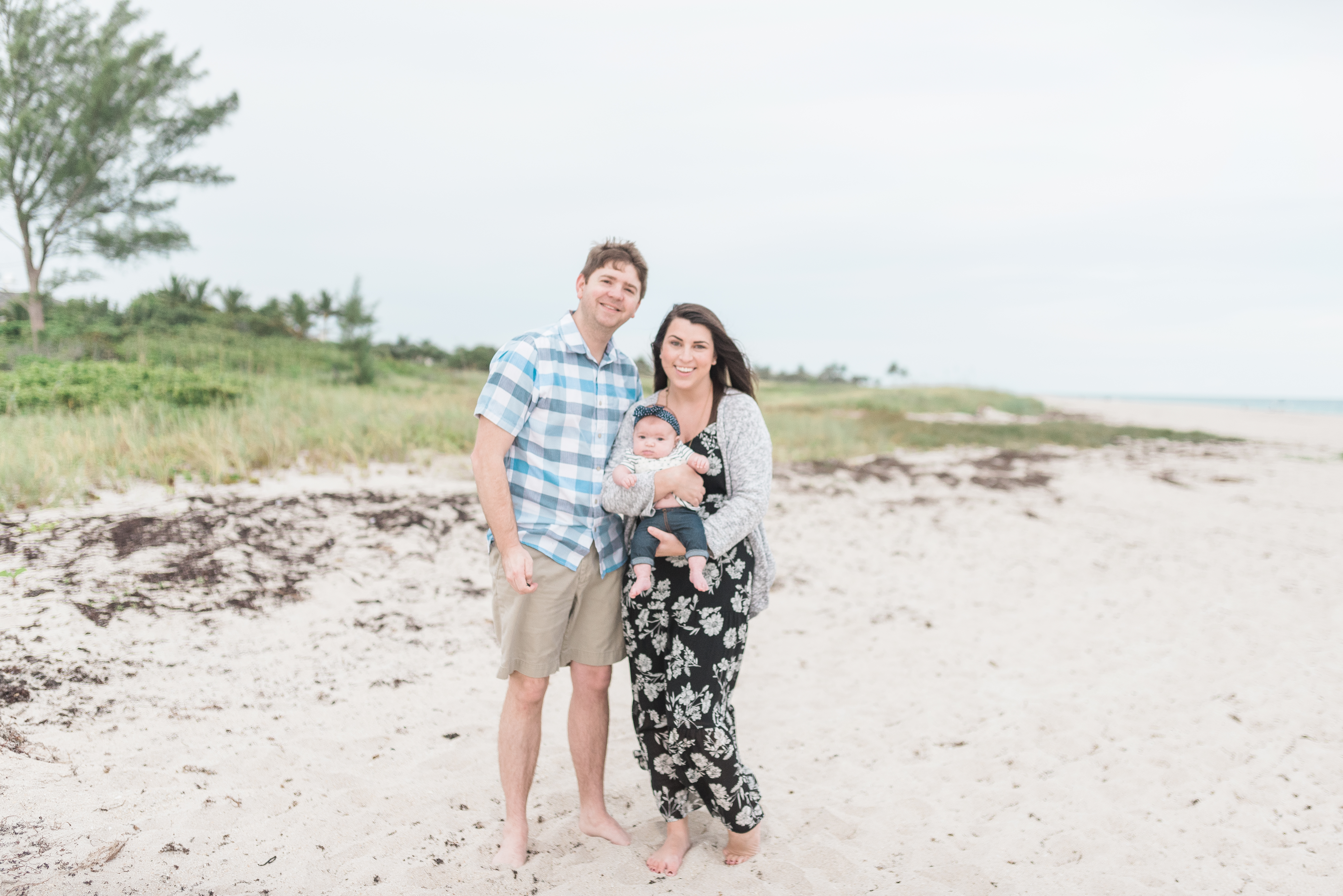 John and Brittney Naylor standing together holding daughter on the beach in Vero Beach