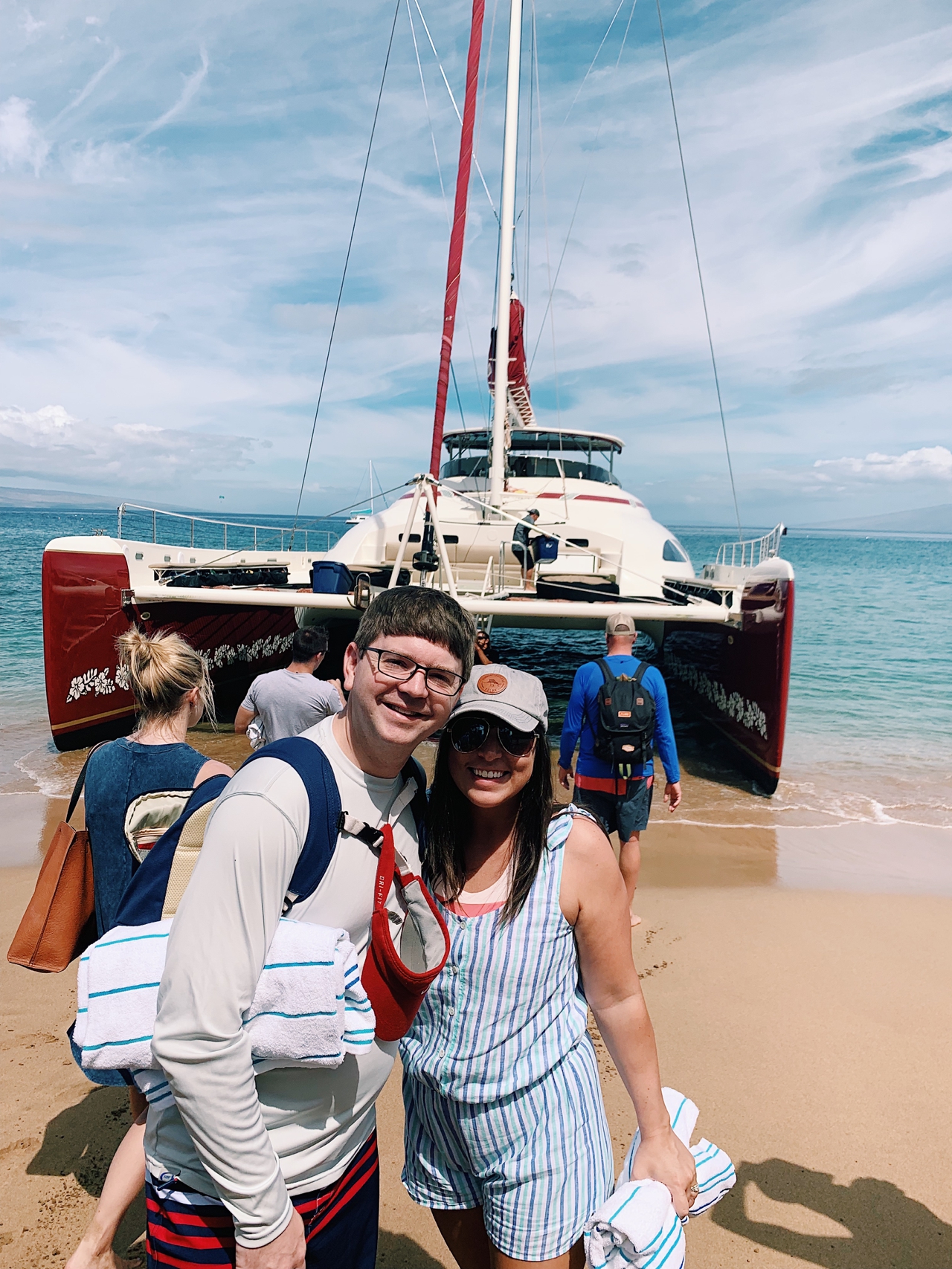 John and Brittney Naylor standing together in front of catamaran in Maui Hawaii