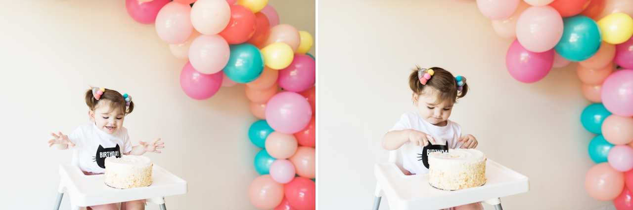 child looking at cake with balloon garland behind her