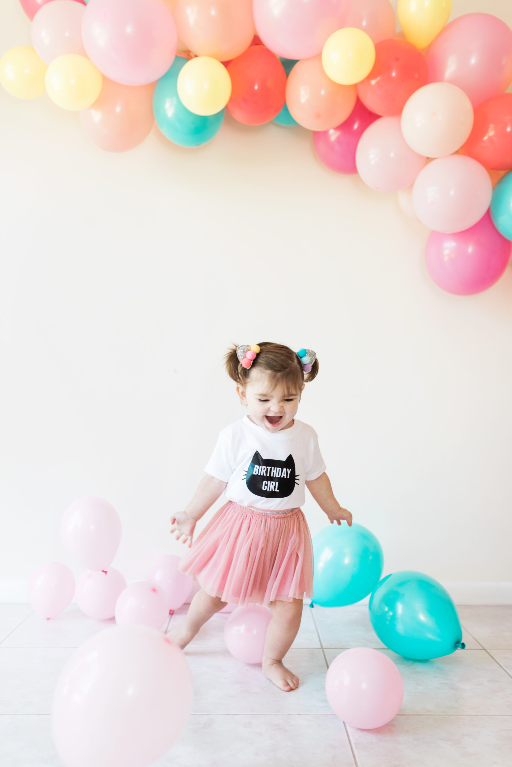 child kicking balloons on floor in birthday outfit