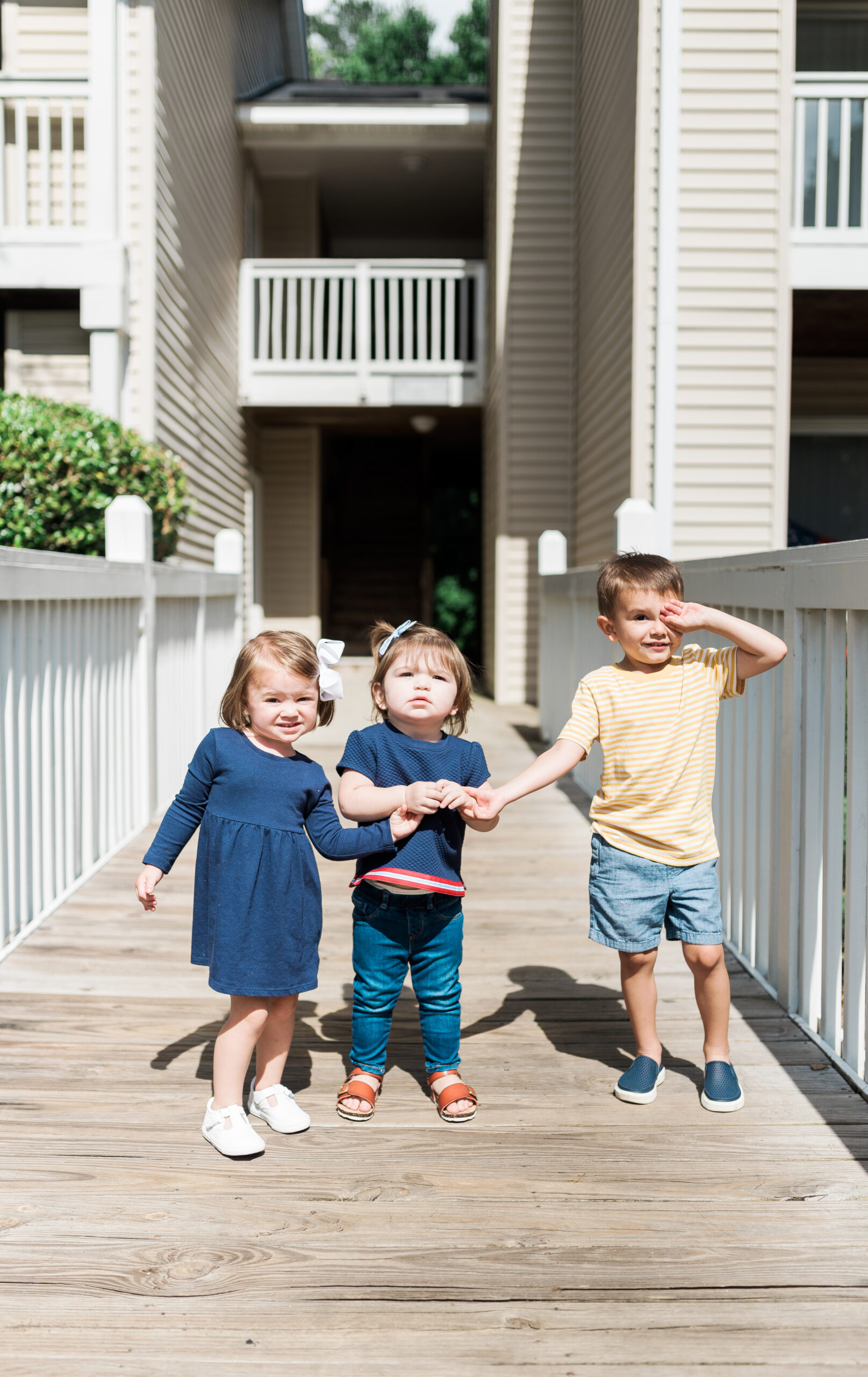 three children holding hands standing on bridge