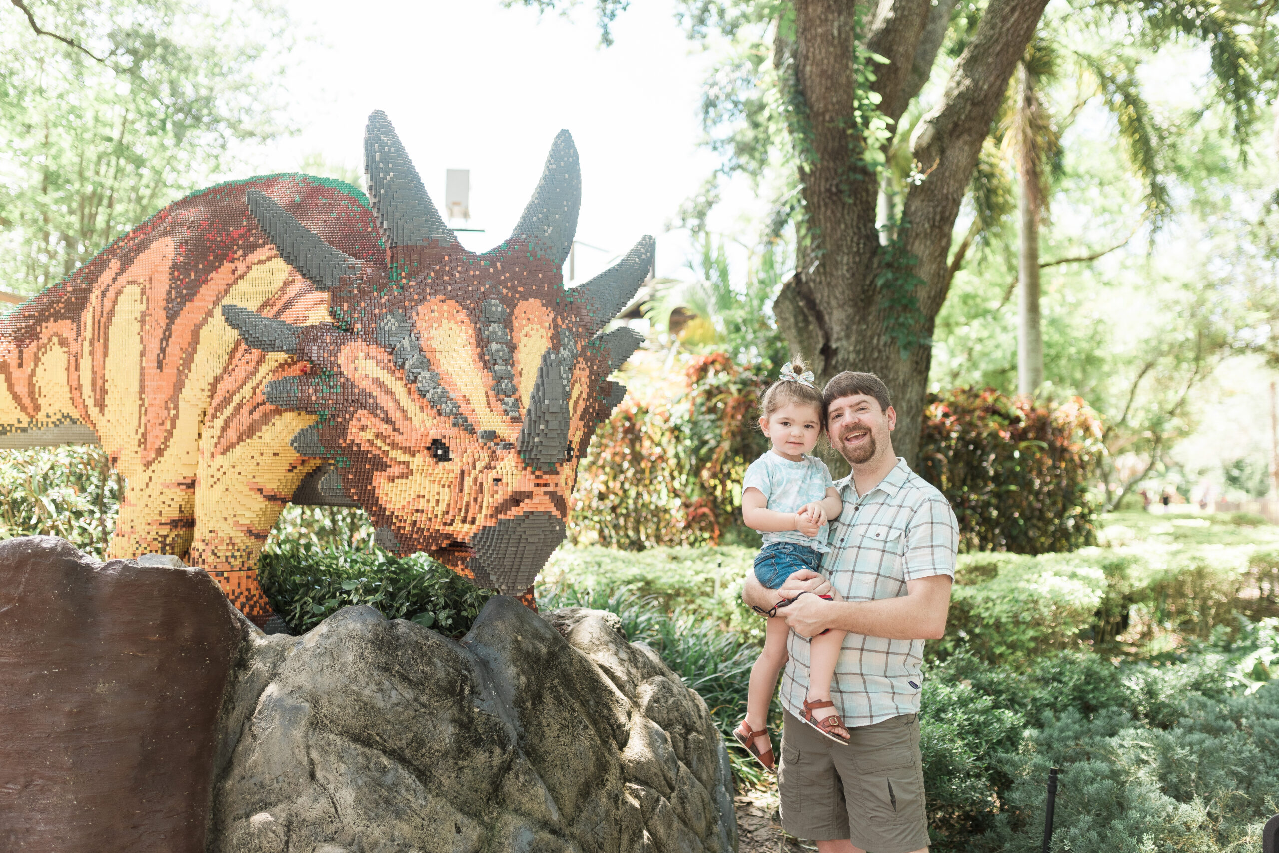 John Naylor holding daughter  standing beside giant LEGO dinosaur at LEGOLAND Florida