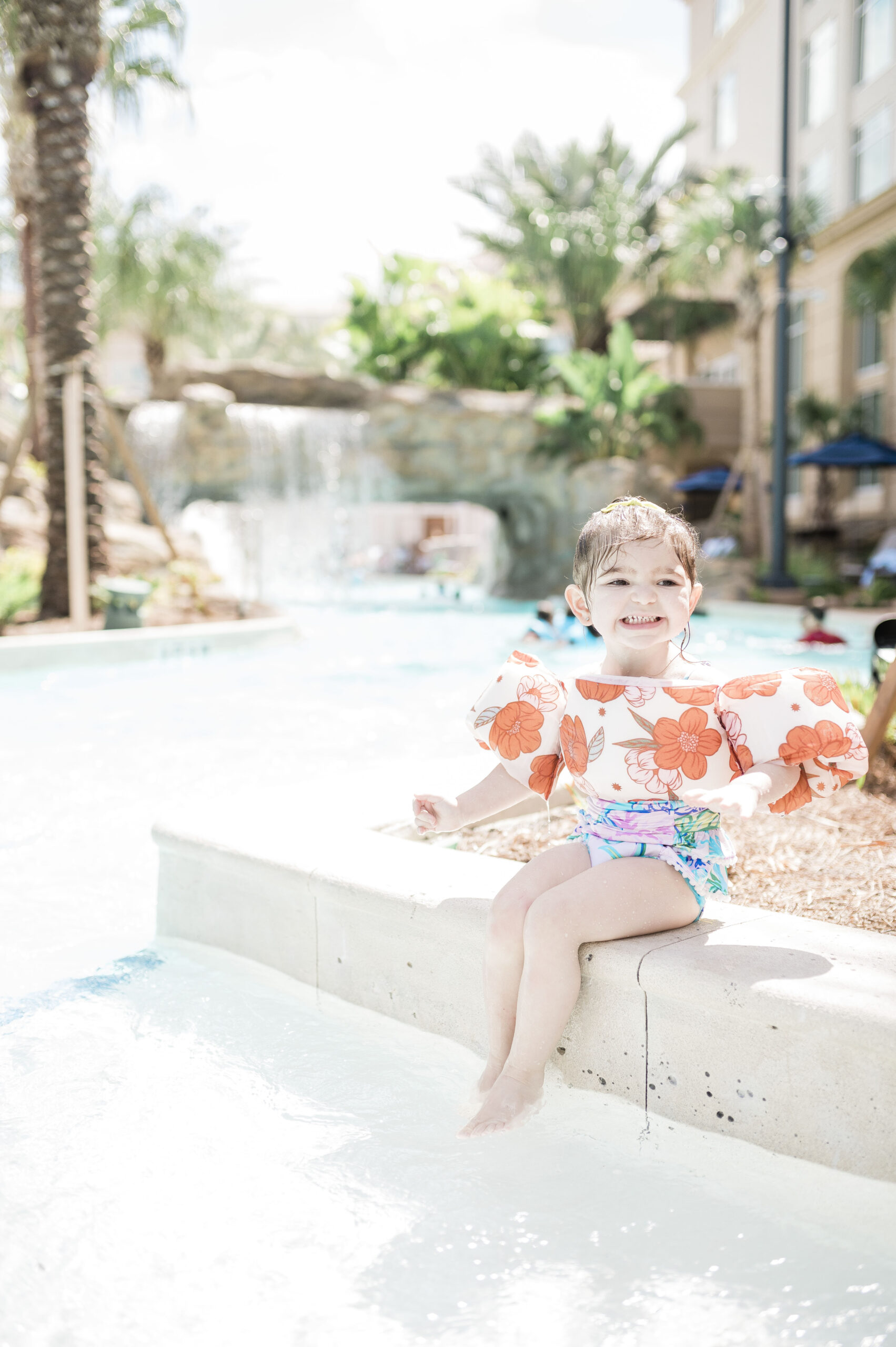 little girl sitting on ledge of pool splashing with feet at gaylord palms