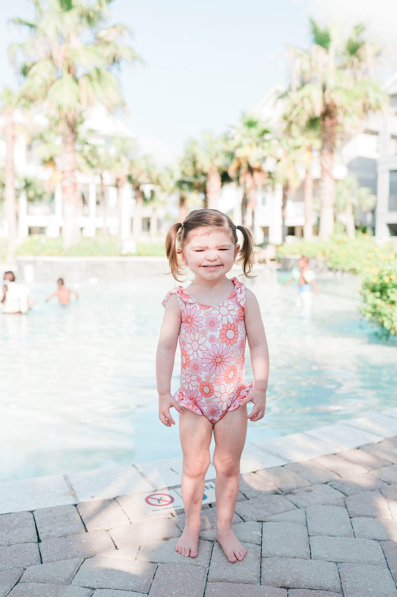 little girl in flower swimsuit at pool