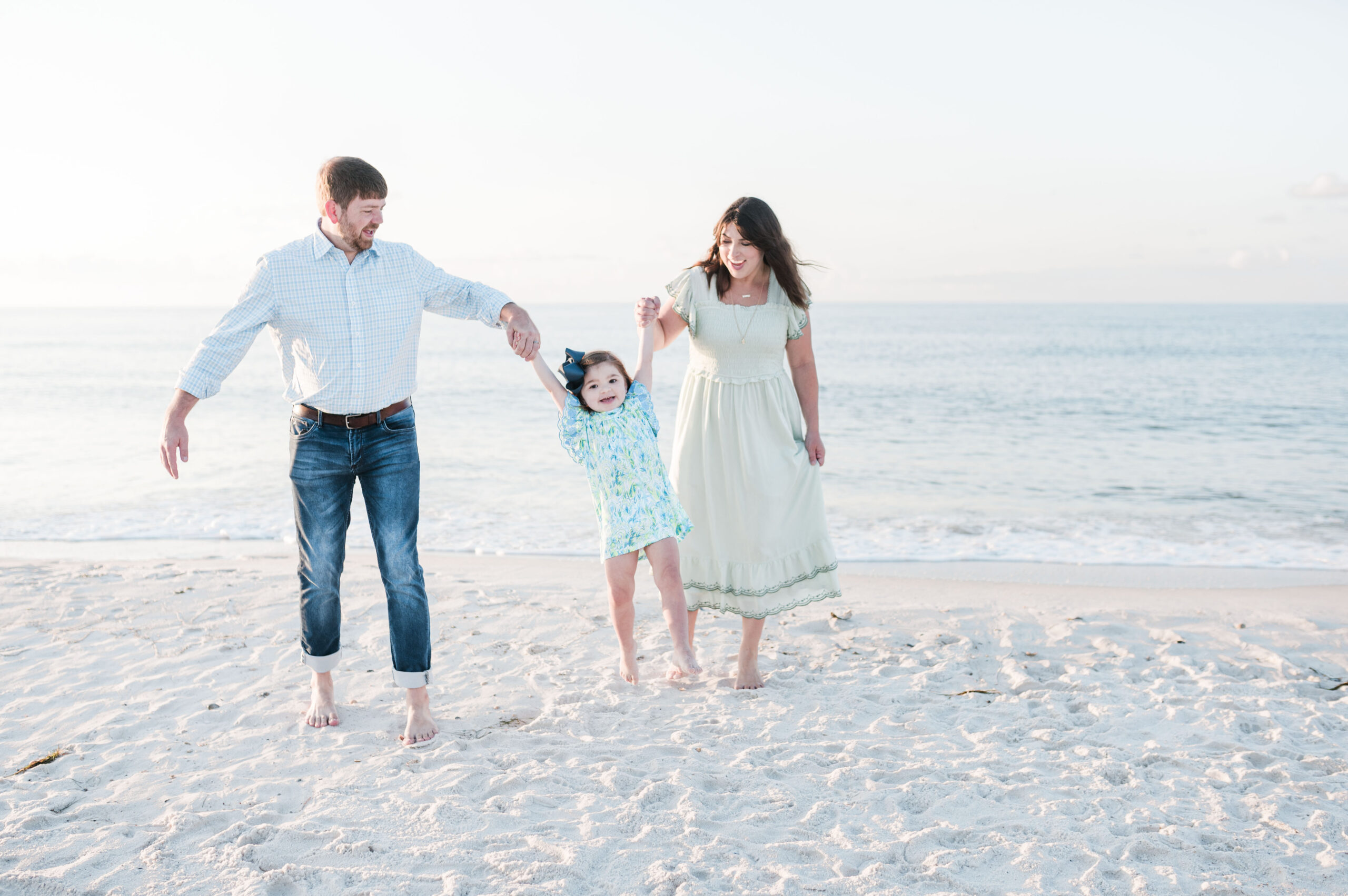 family of three walking on gulf shores beach in alabama