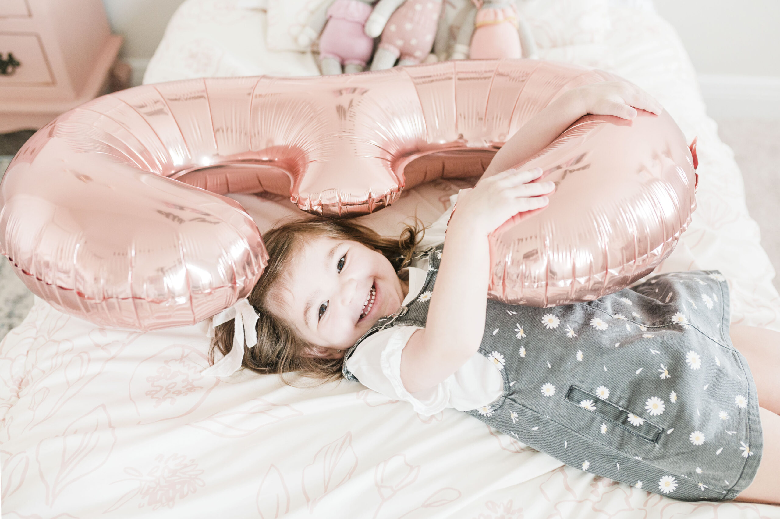 Eleanor with large balloon shaped as the number 3 laying on bed