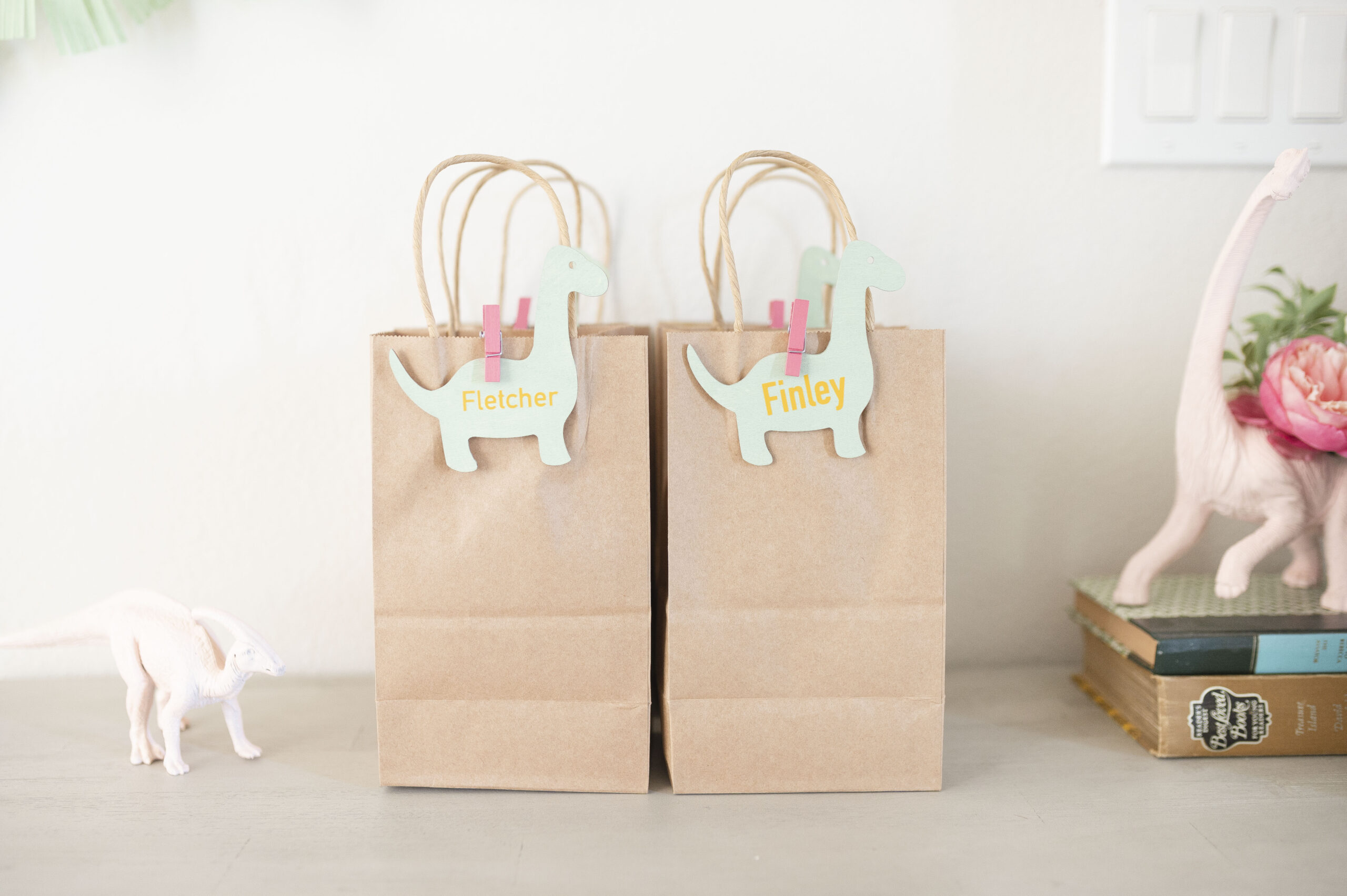 Goody bags for Three Rex birthday party featuring brown bags and green dinosaur
