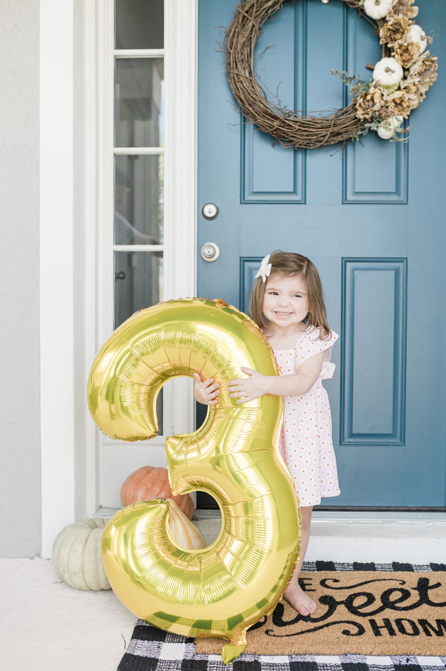 eleanor with gold 3 balloon standing outside in floral dress