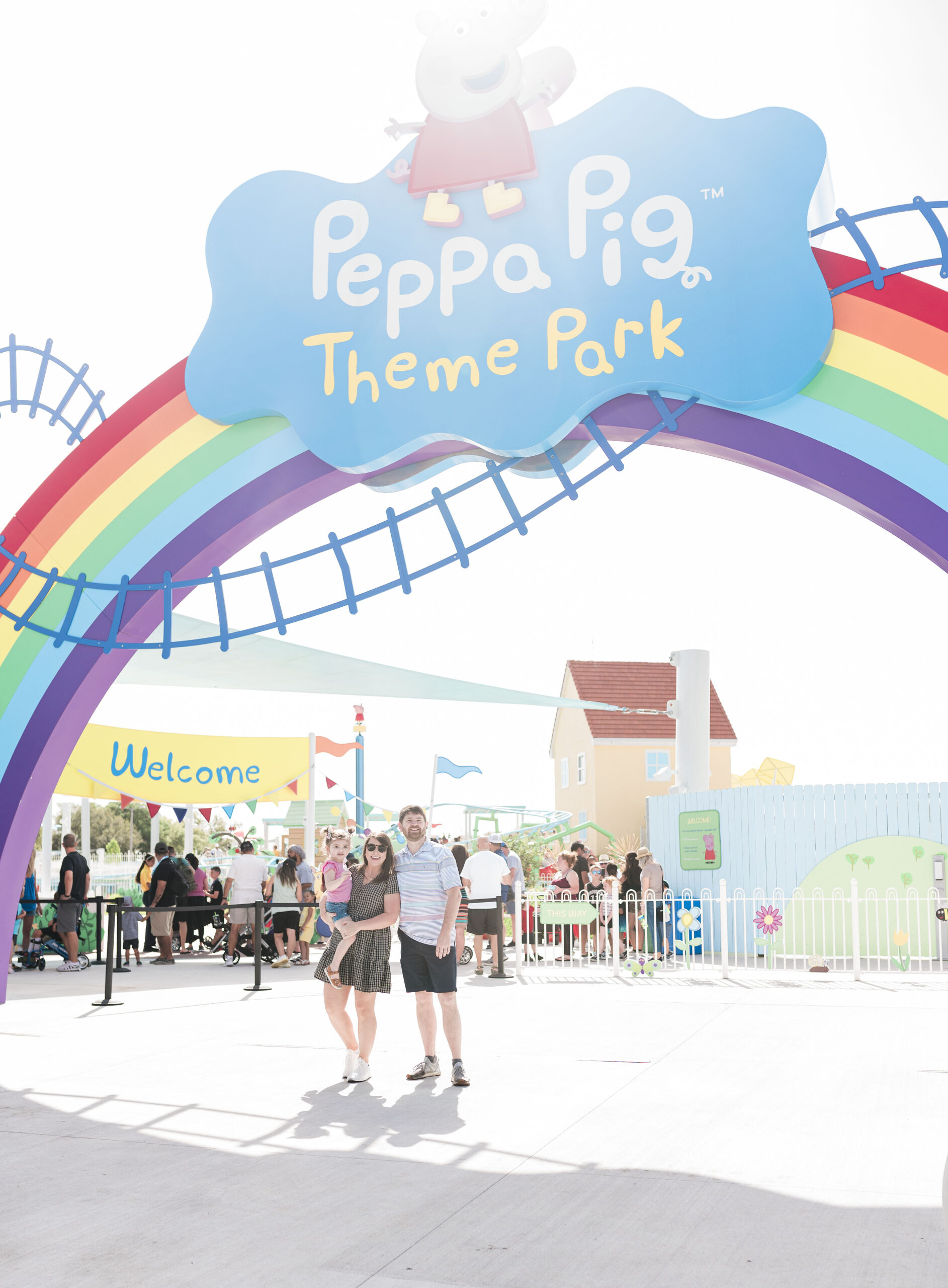 family standing outside peppa pig theme park florida under rainbow and peppa pig logo