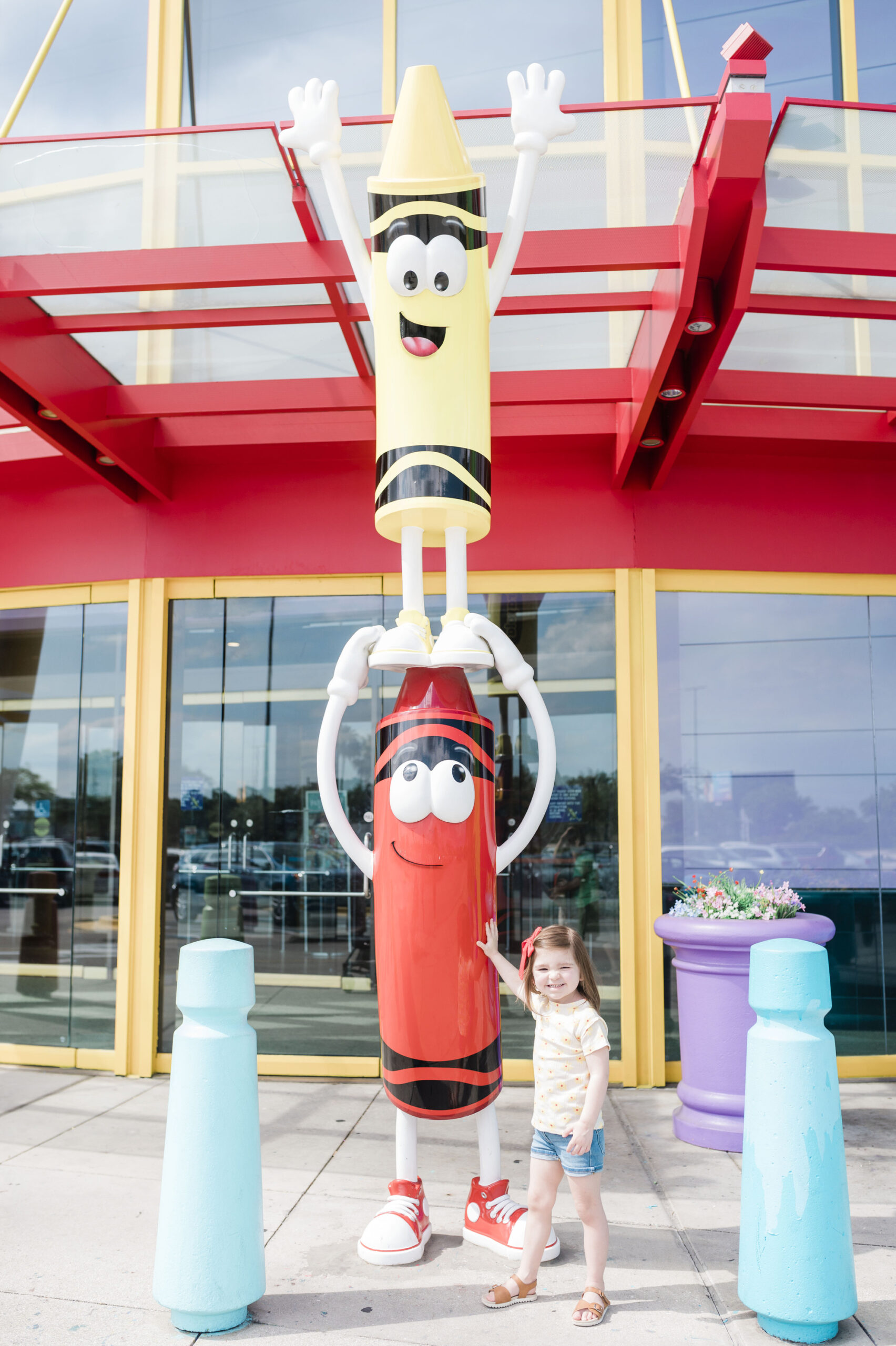 little girl standing beside lifesize crayons at crayola experience