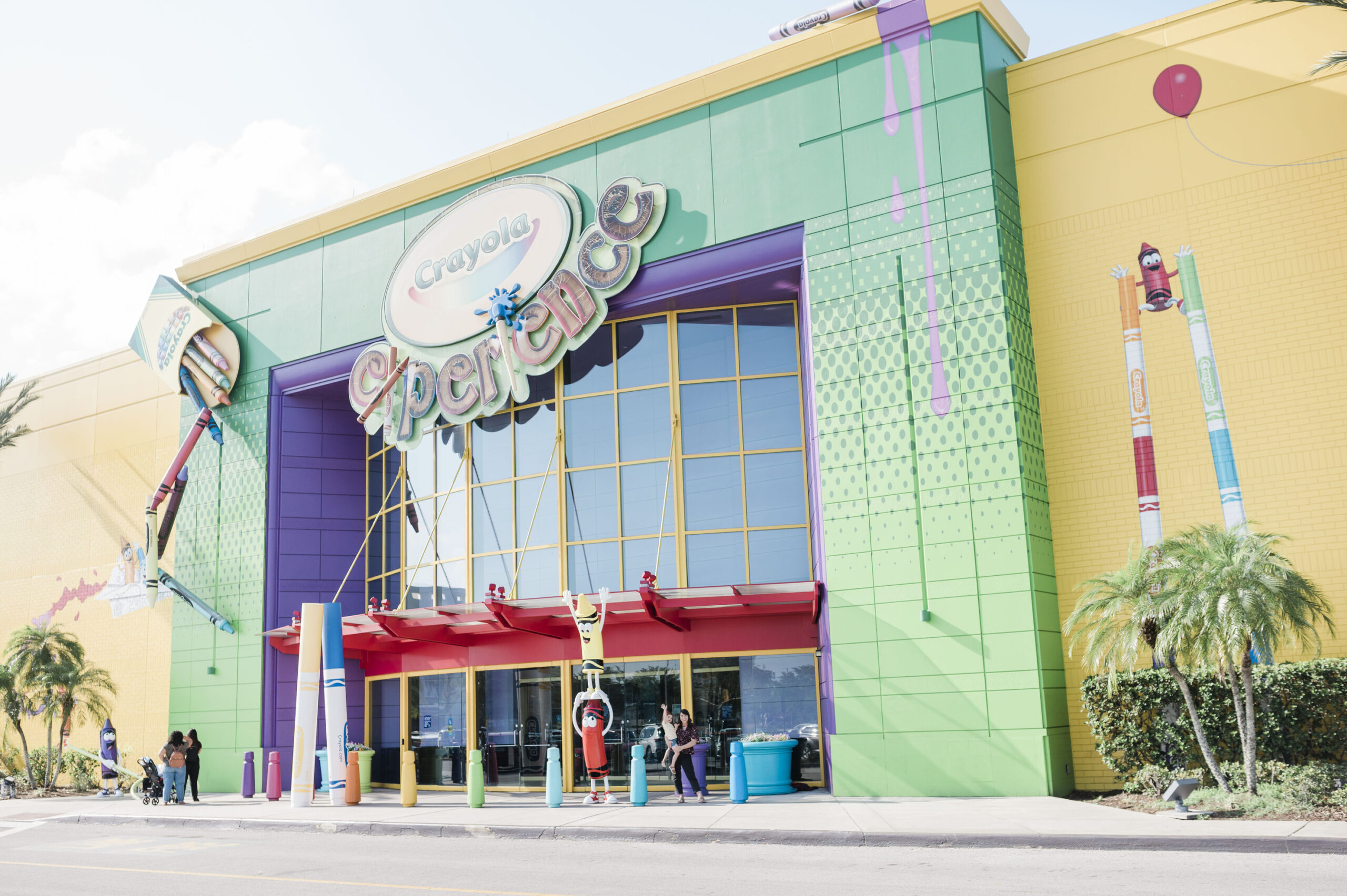 crayola experience orlando, family standing outside large colorful building with lifesize crayons