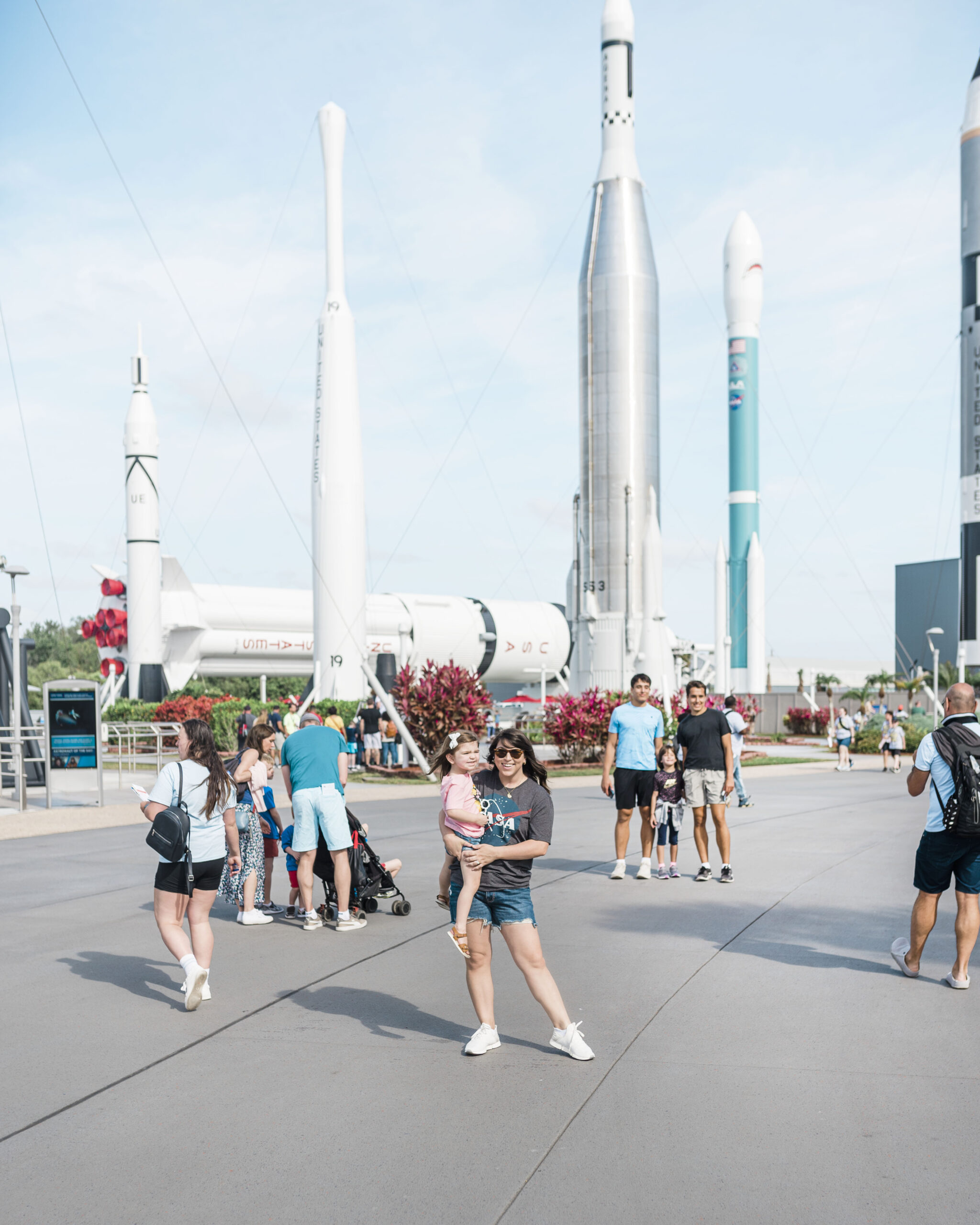 woman and child standing in front of large rockets at Kennedy space center