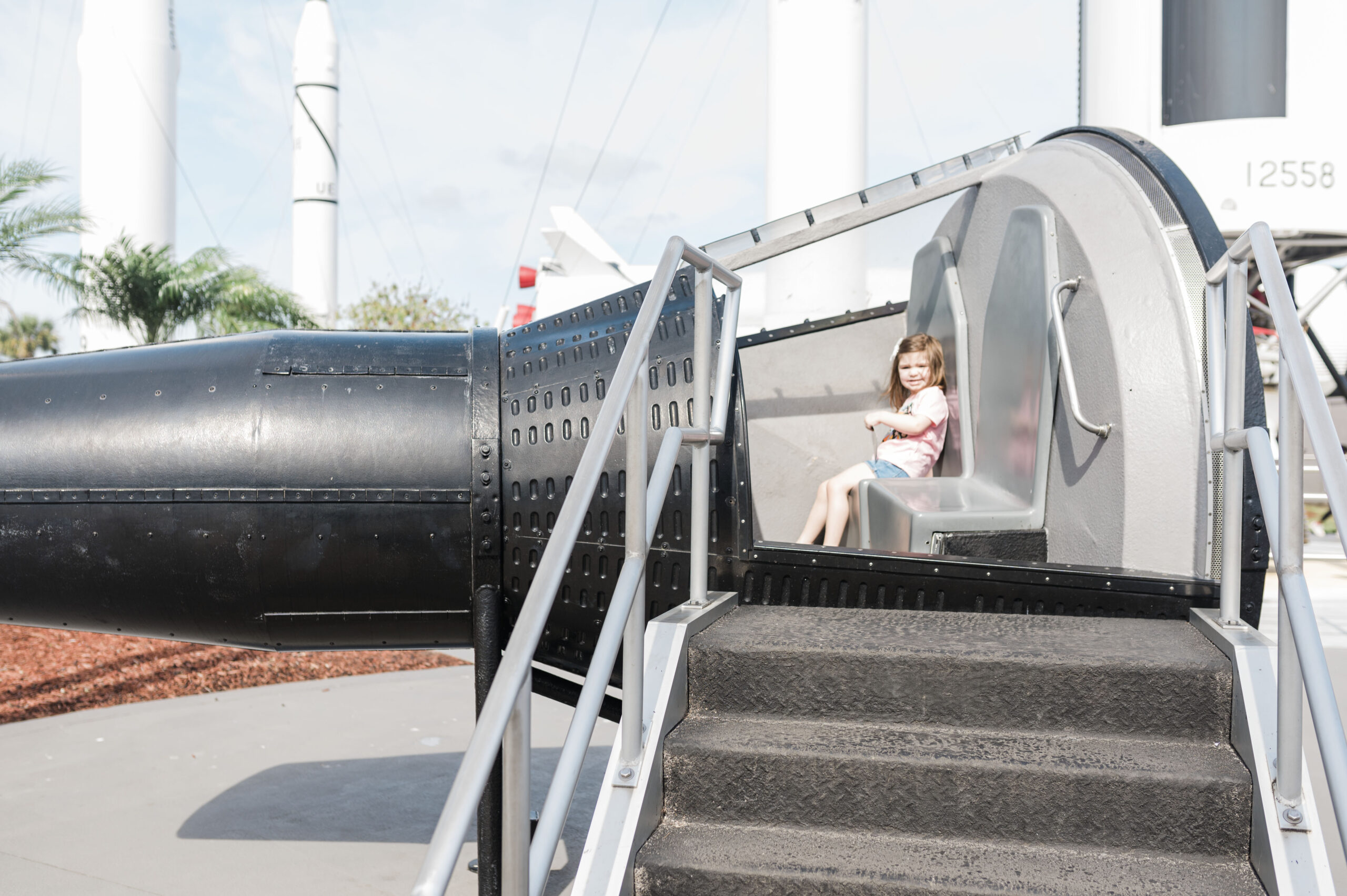 little girl sitting inside space rocket at Kennedy space center in florida