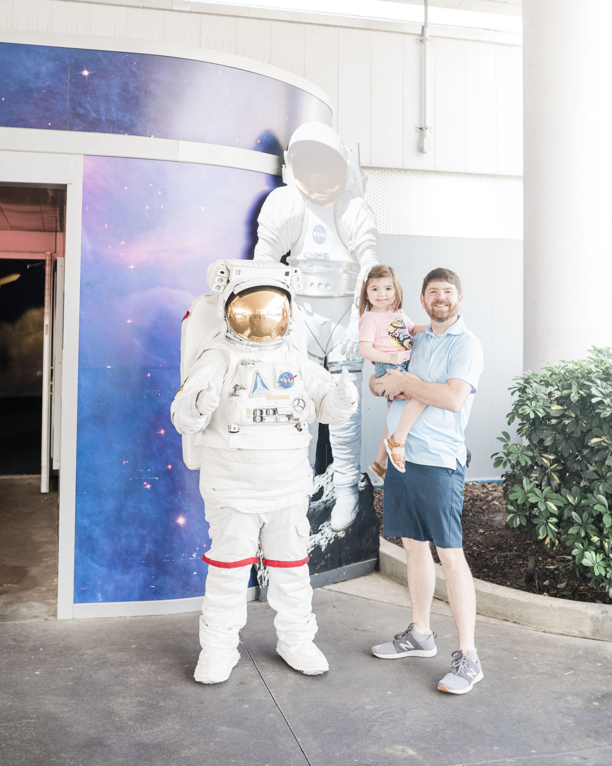 man and child standing with astronaut at Kennedy space center