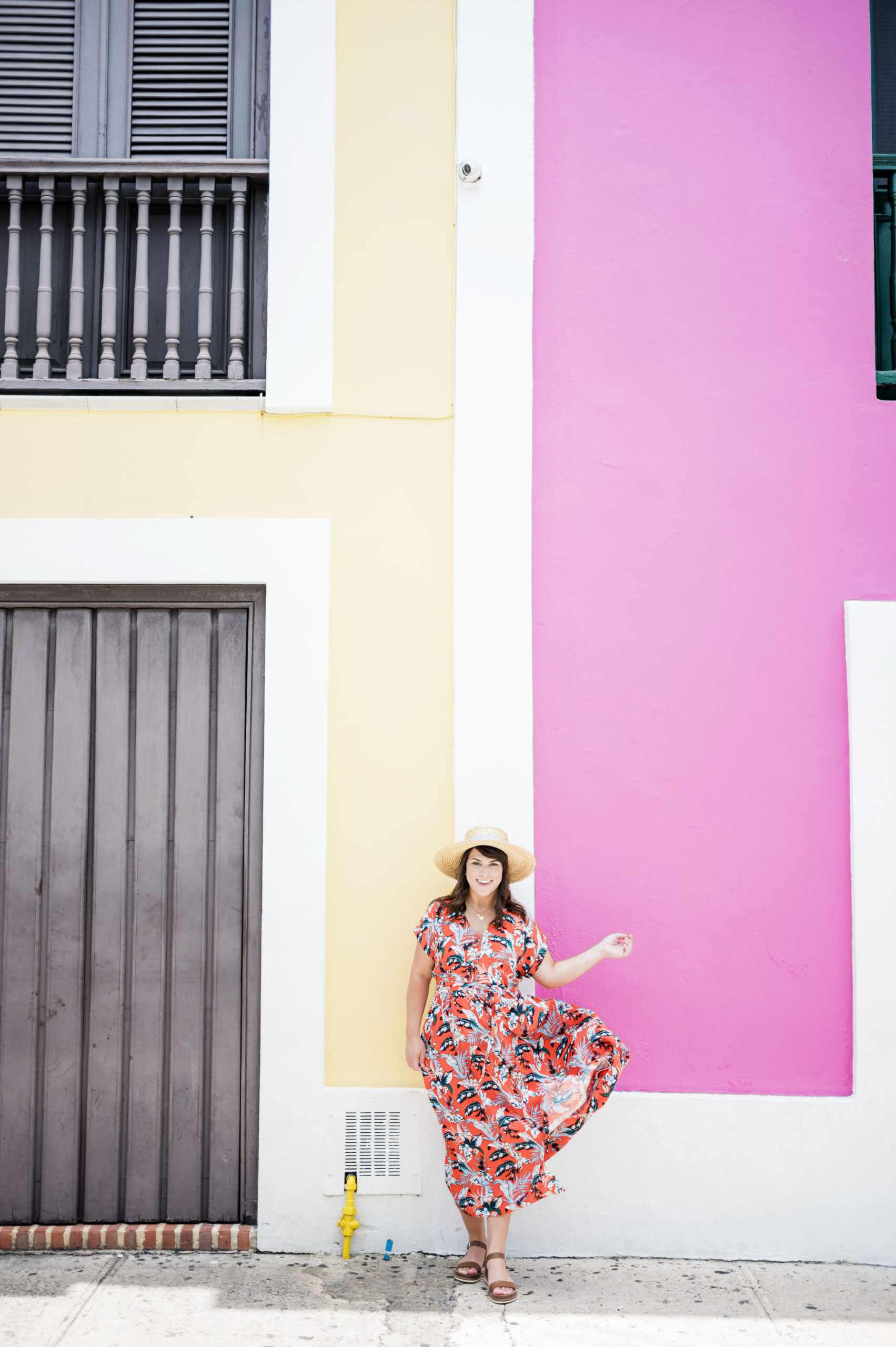 yellow and pink wall, female in front tossing dress skirt in air