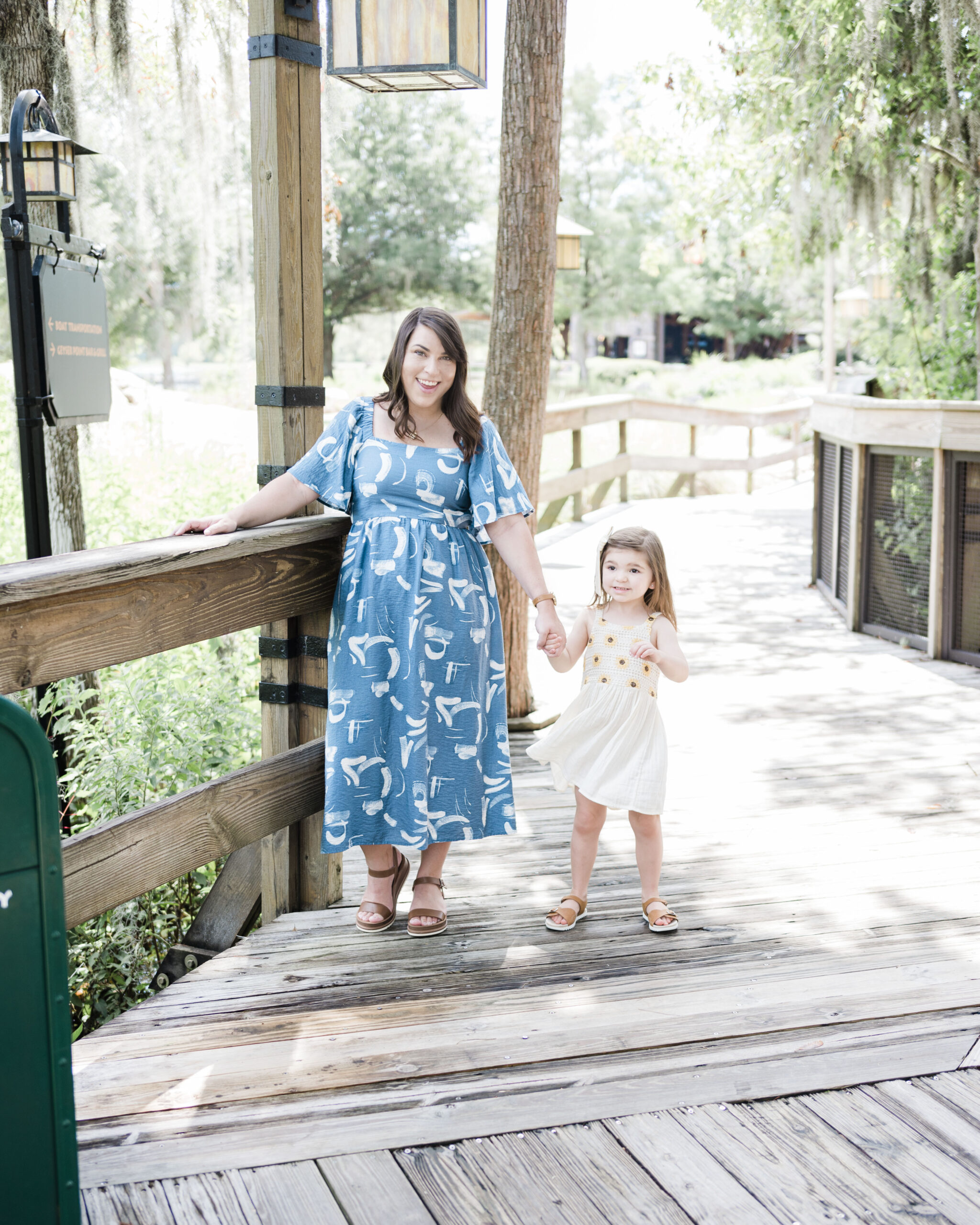 brittney naylor wearing blue dress holding hands with daughter outside at disney's wilderness lodge