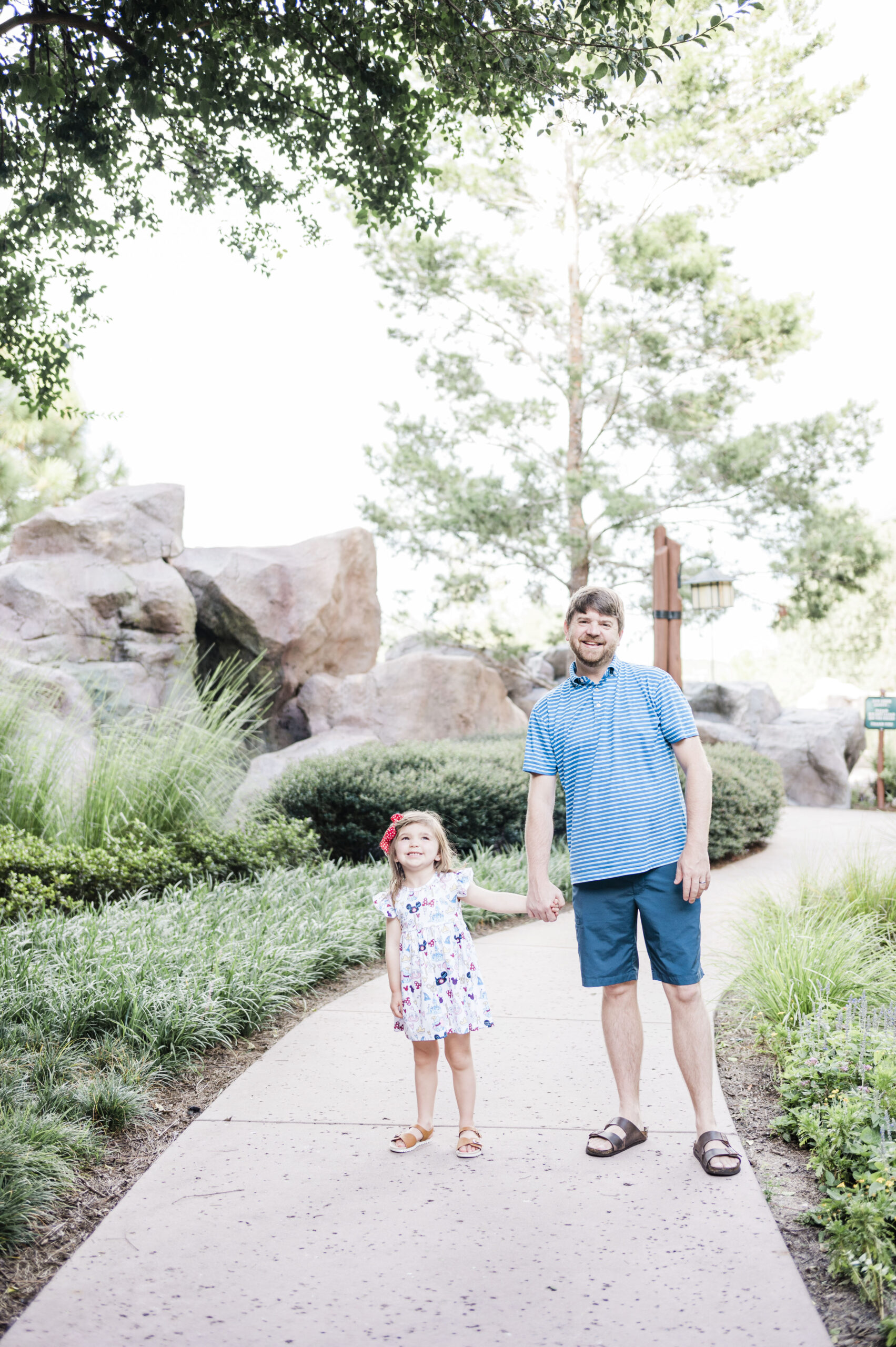 John Naylor and daughter holding hands outside on sidewalk at Disney's Wilderness Lodge
