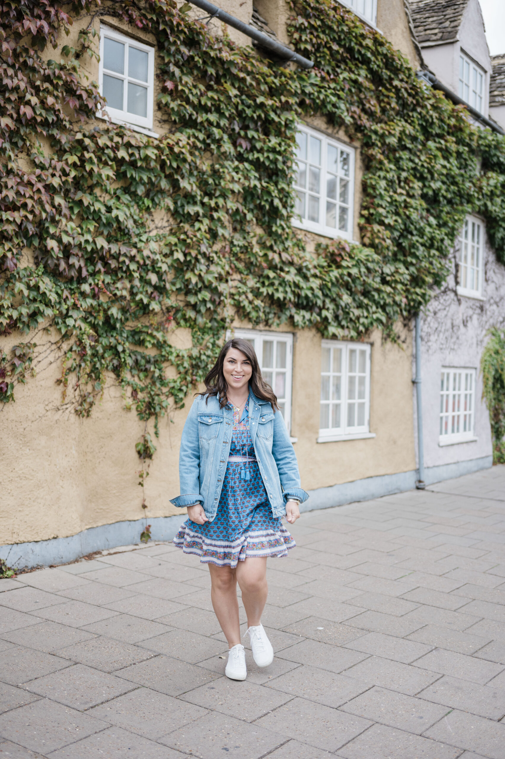 Brittney Naylor in blue dress and denim jacket walking the streets of oxford london