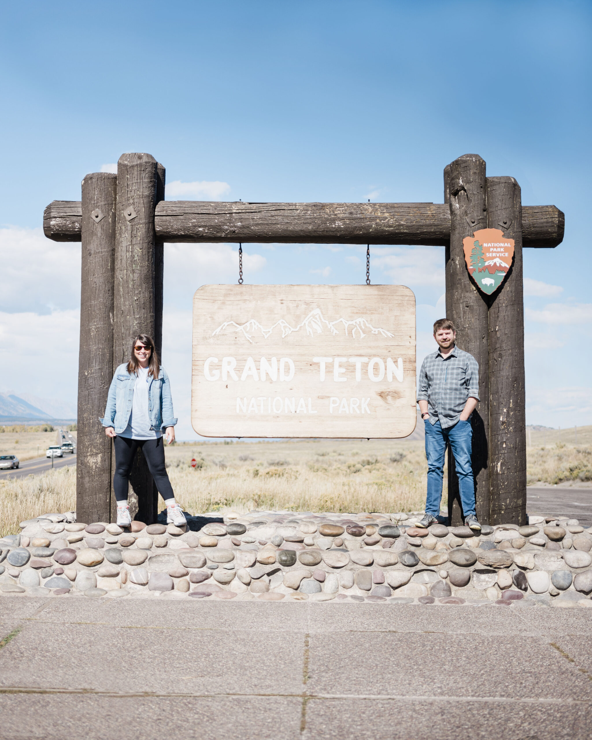 John and Brittney Naylor standing beside the Grand Teton National Park sign in Wyoming
