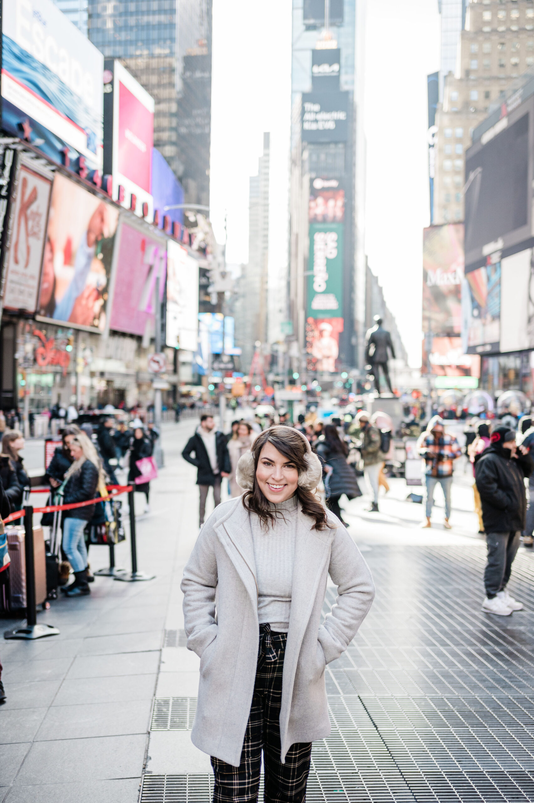 Brittney Naylor in gray petticoat and ear muffs standing in Time Square in New York City.