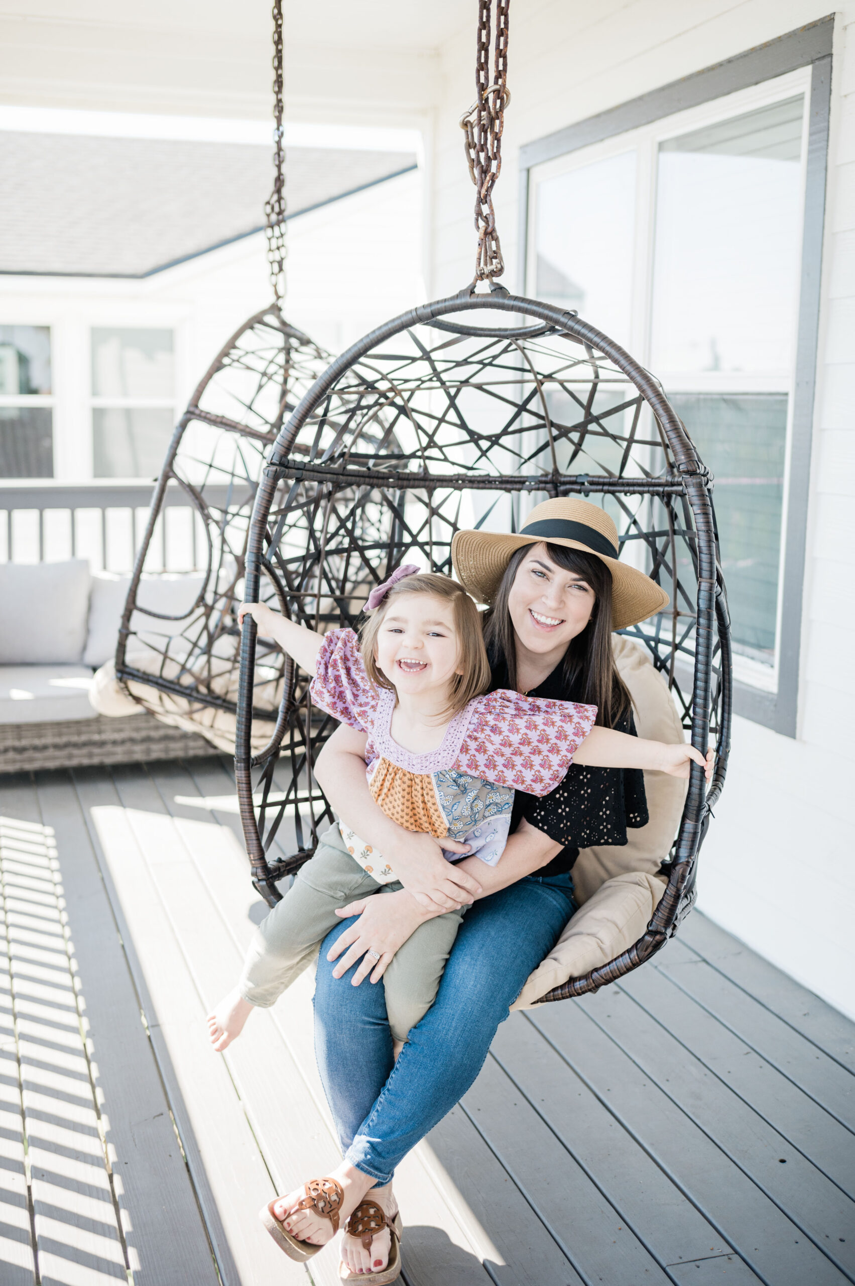 Brittney Naylor and daughter in wicker swing on porch of their airbnb in Saint Augustine Florida