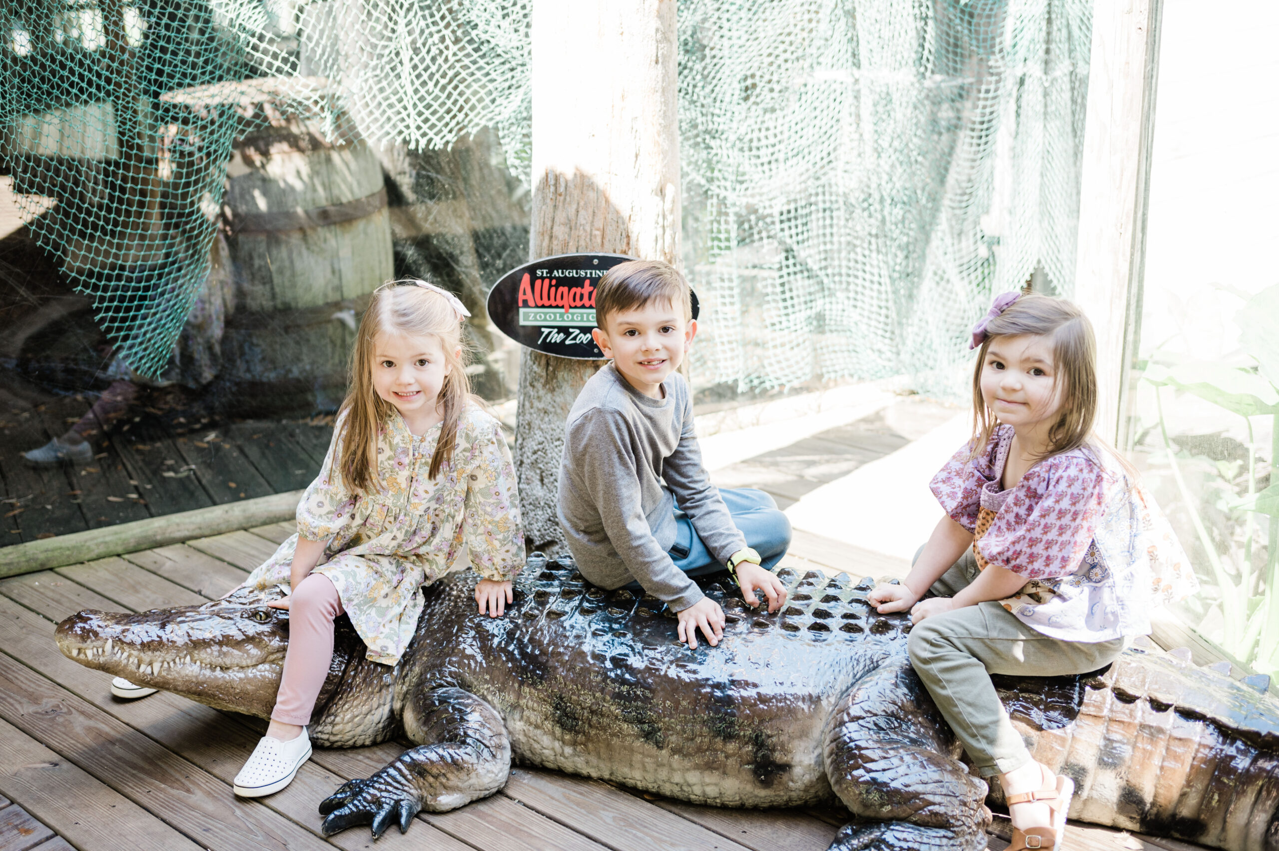Three children sitting on fake alligator at the Alligator Farm in Saint Augustine, Florida