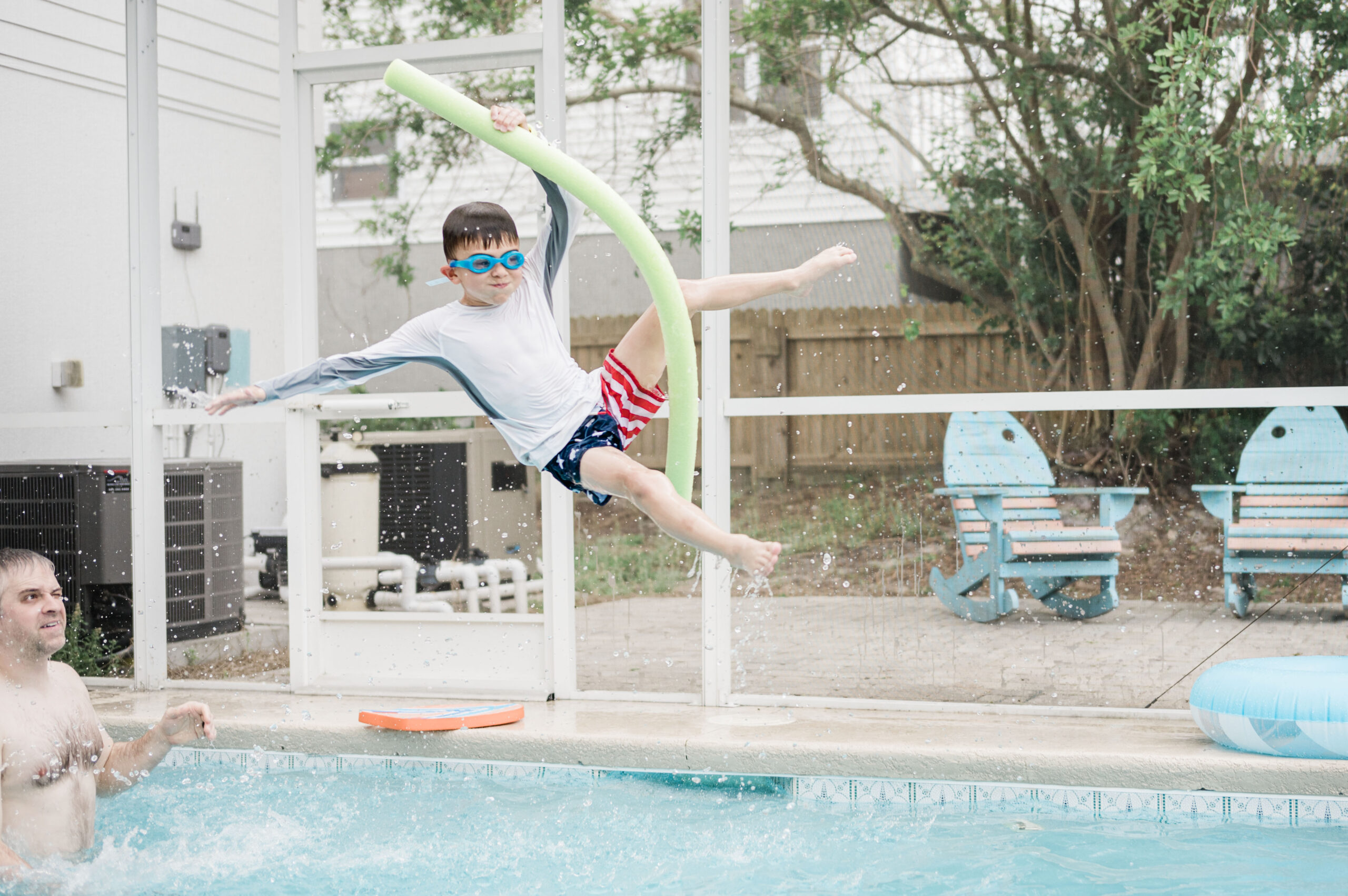 boy thrown in air with pool noodle coming down making a splash in the pool, airbnb pool in saint augustine