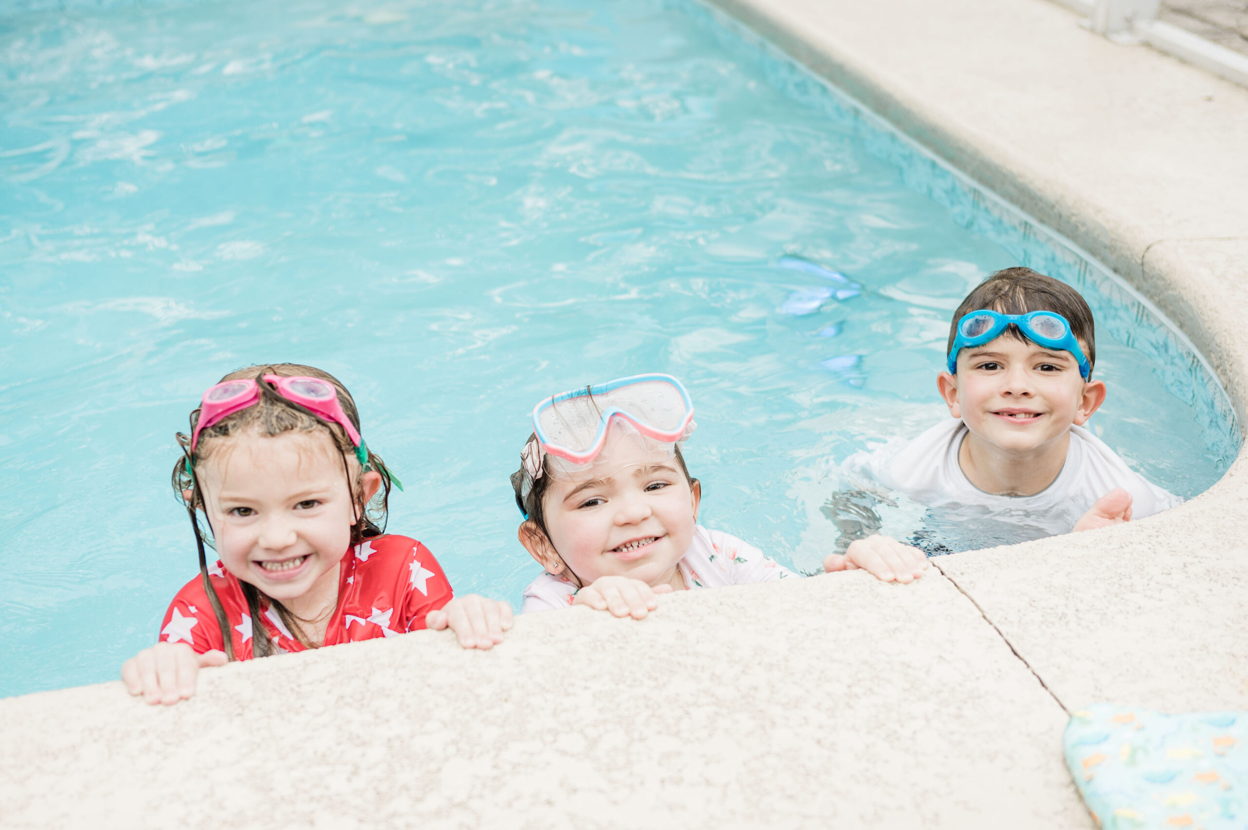 3 small kids posing on edge of pool with goggles on top of their head, airbnb saint augustine