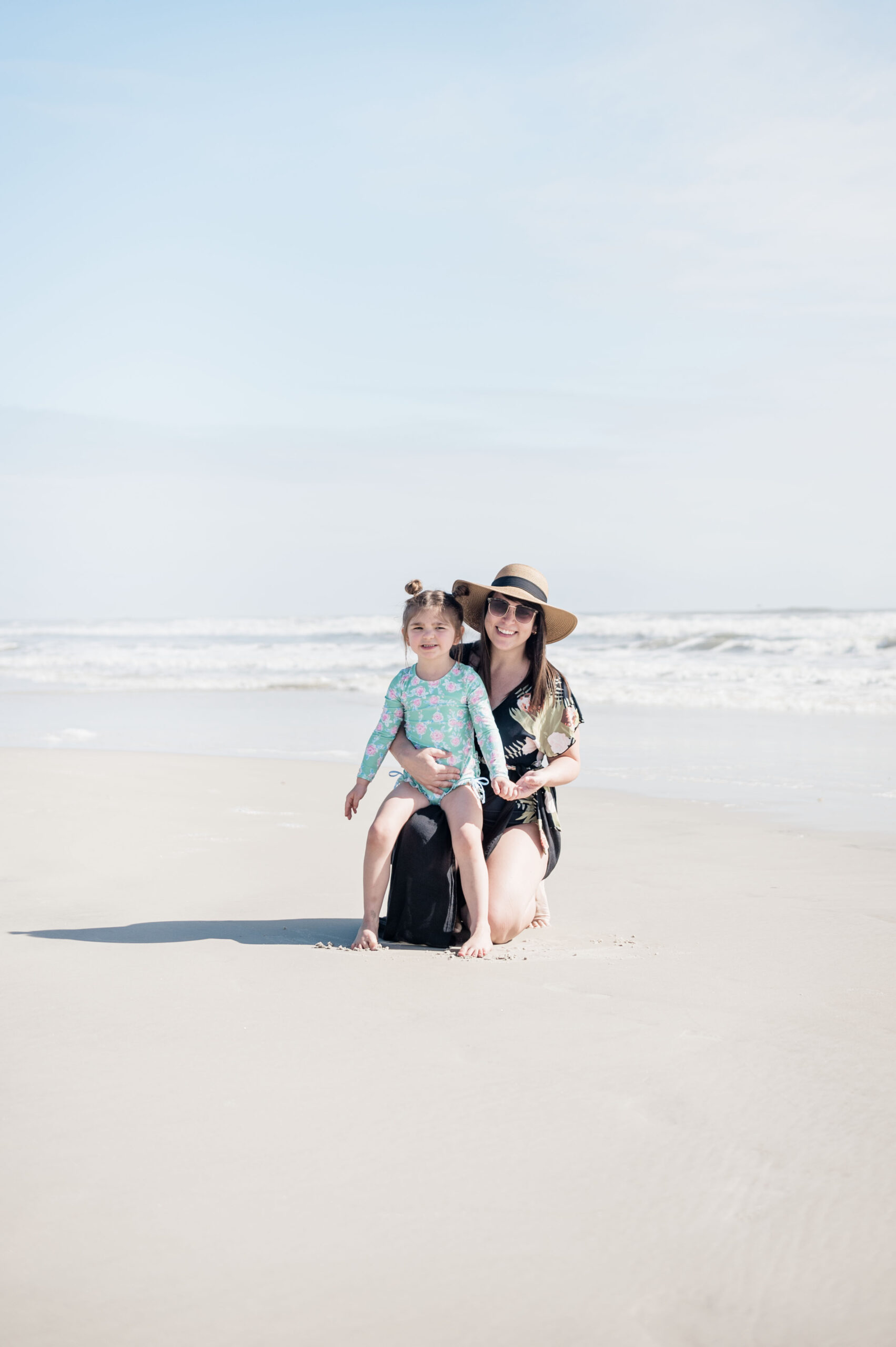 Brittney Naylor and daughter posing together on the beach in saint augustine with the waves in the background
