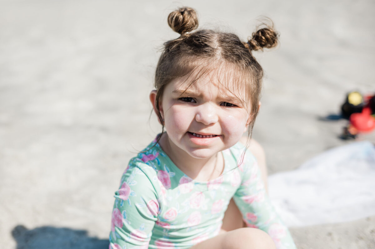 Eleanor Naylor grinning at the beach in Saint Augustine, Florida wearing swim suit and hair in space buns