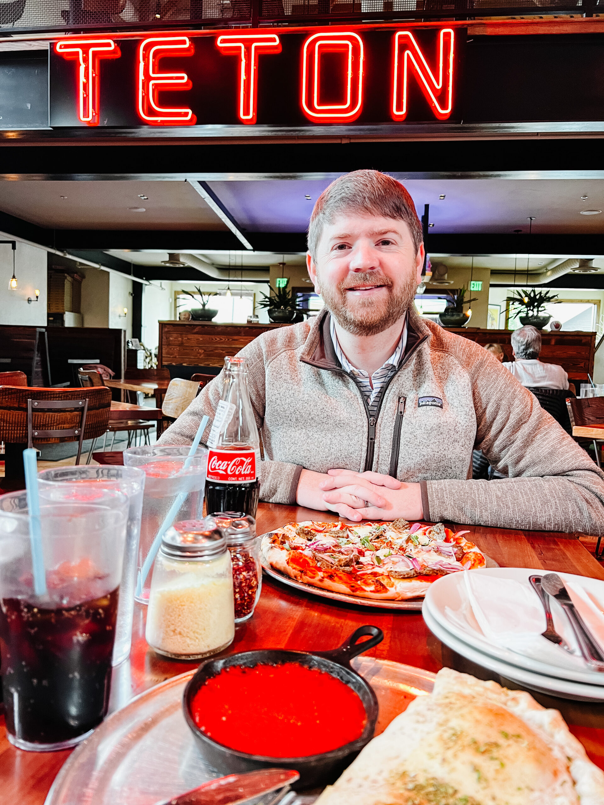 John Naylor sitting in Teton Handfire Pizza in Jackson Hole Wyoming. Pizza is sitting out in front of him. 