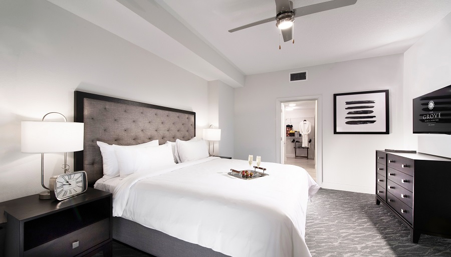 Interior bedroom of a suite at The Grove Resort and Water Park Orlando, shows a king bed and entrance to master bathroom.