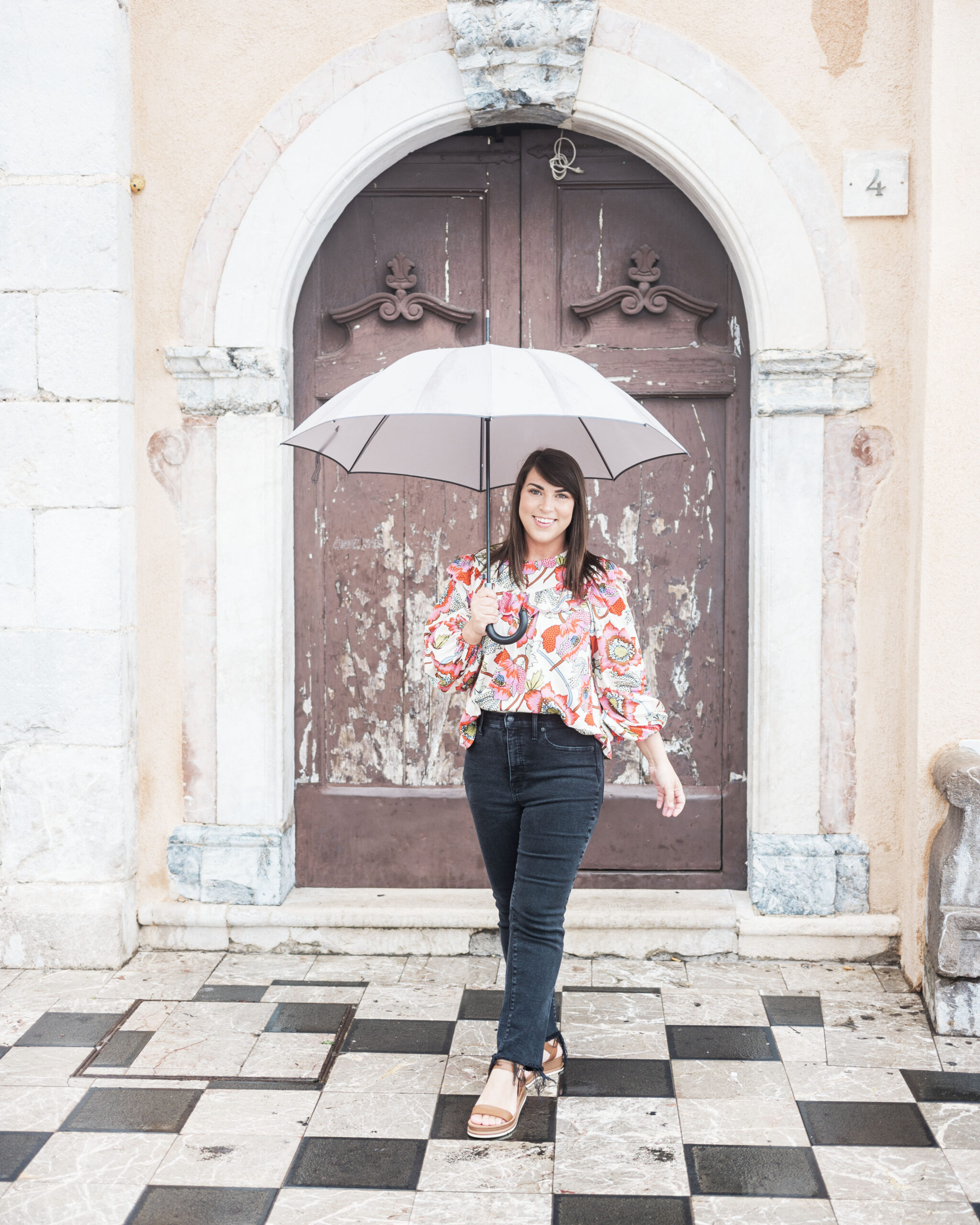 Brittney Naylor holding umbrella, standing in front of old building in Taormina, Sicily