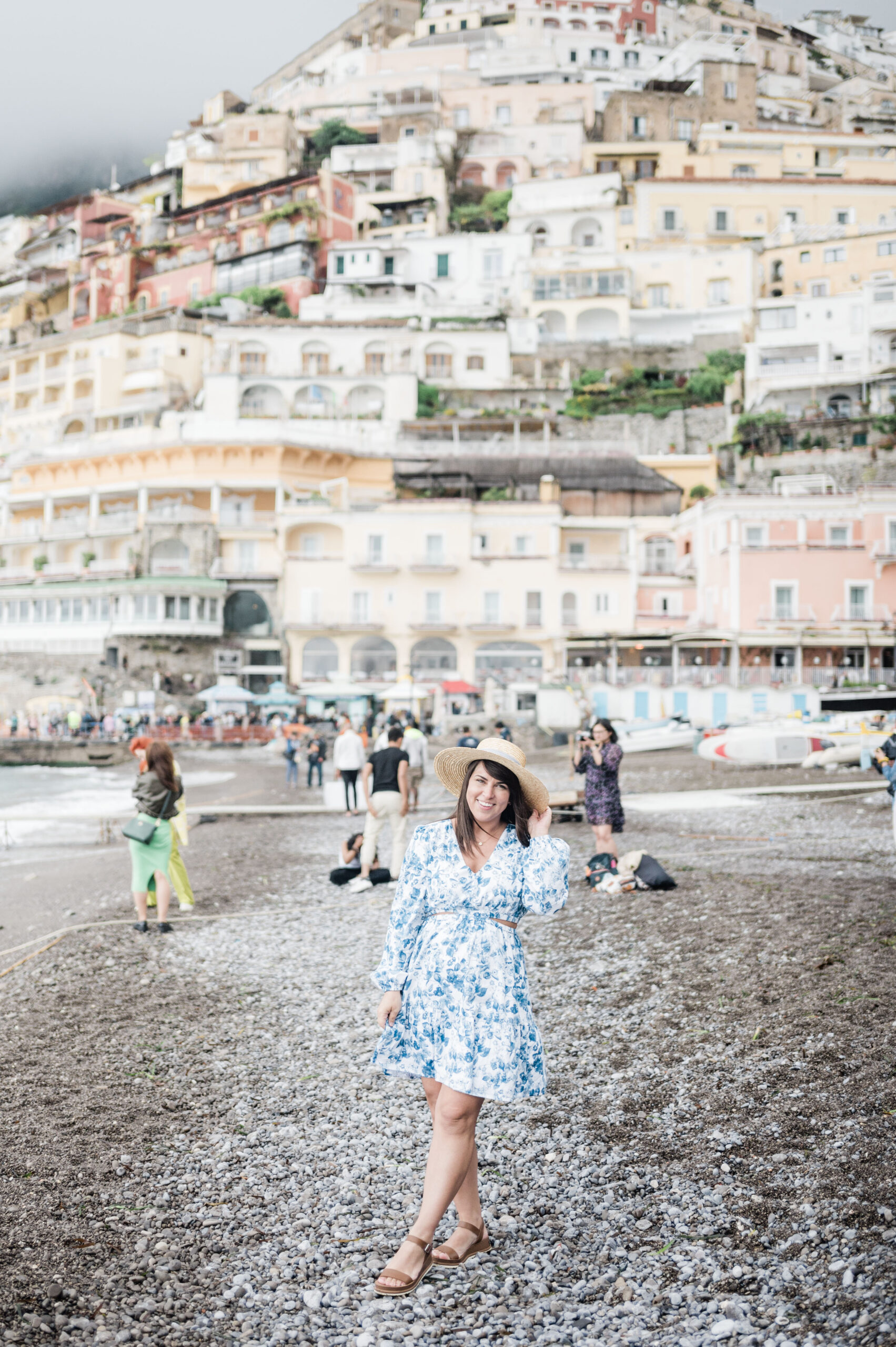 Brittney Naylor standing on beach in Positano Italy with city behind her