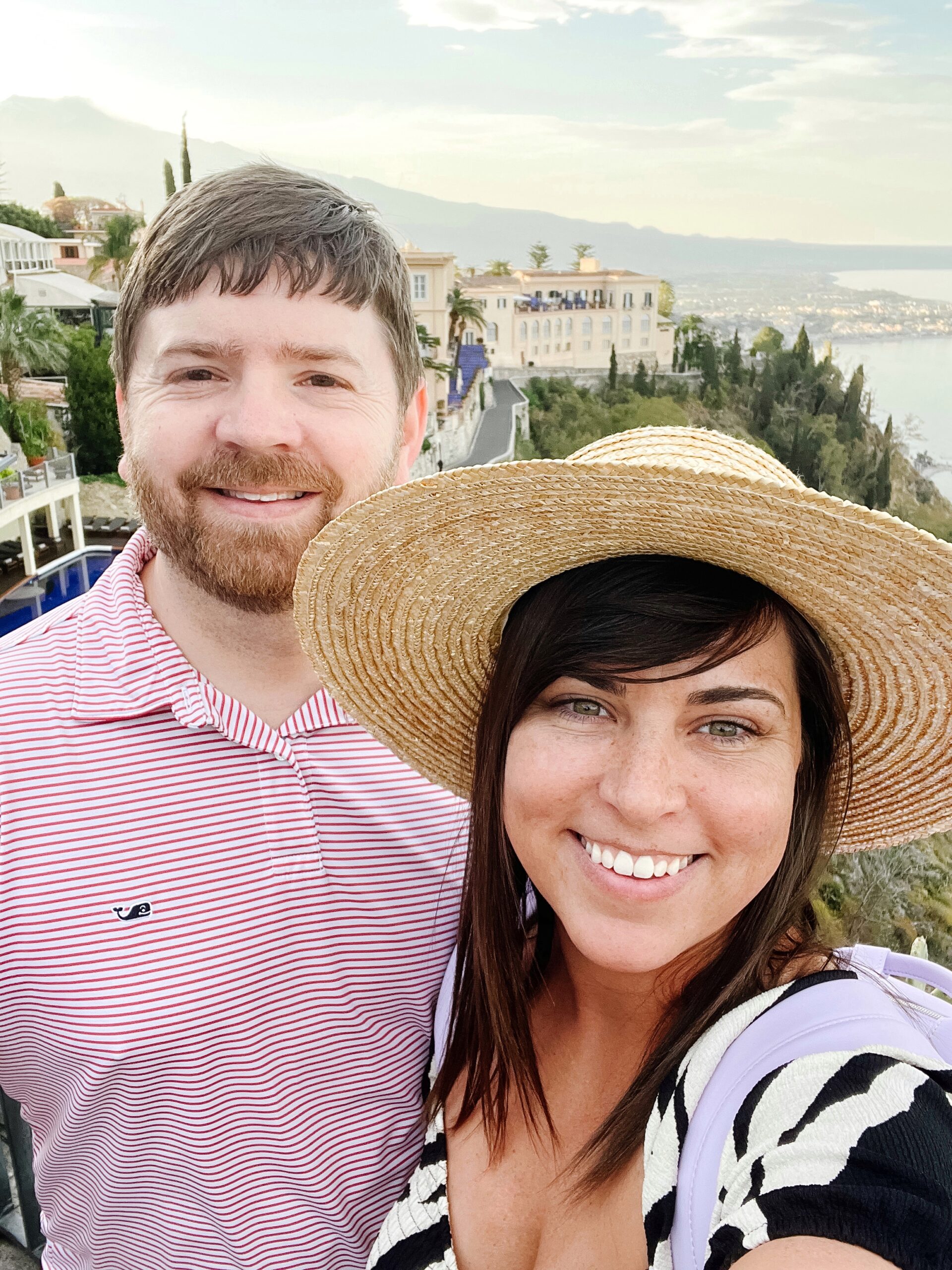 John and Brittney Naylor taking a selfie with Taormina and Mount Etna behind them. 10 day Italy Itinerary.