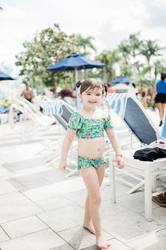 Eleanor walking back from the water splash area wearing a green swimsuit at The Grove Resort and Water Park Orlando
