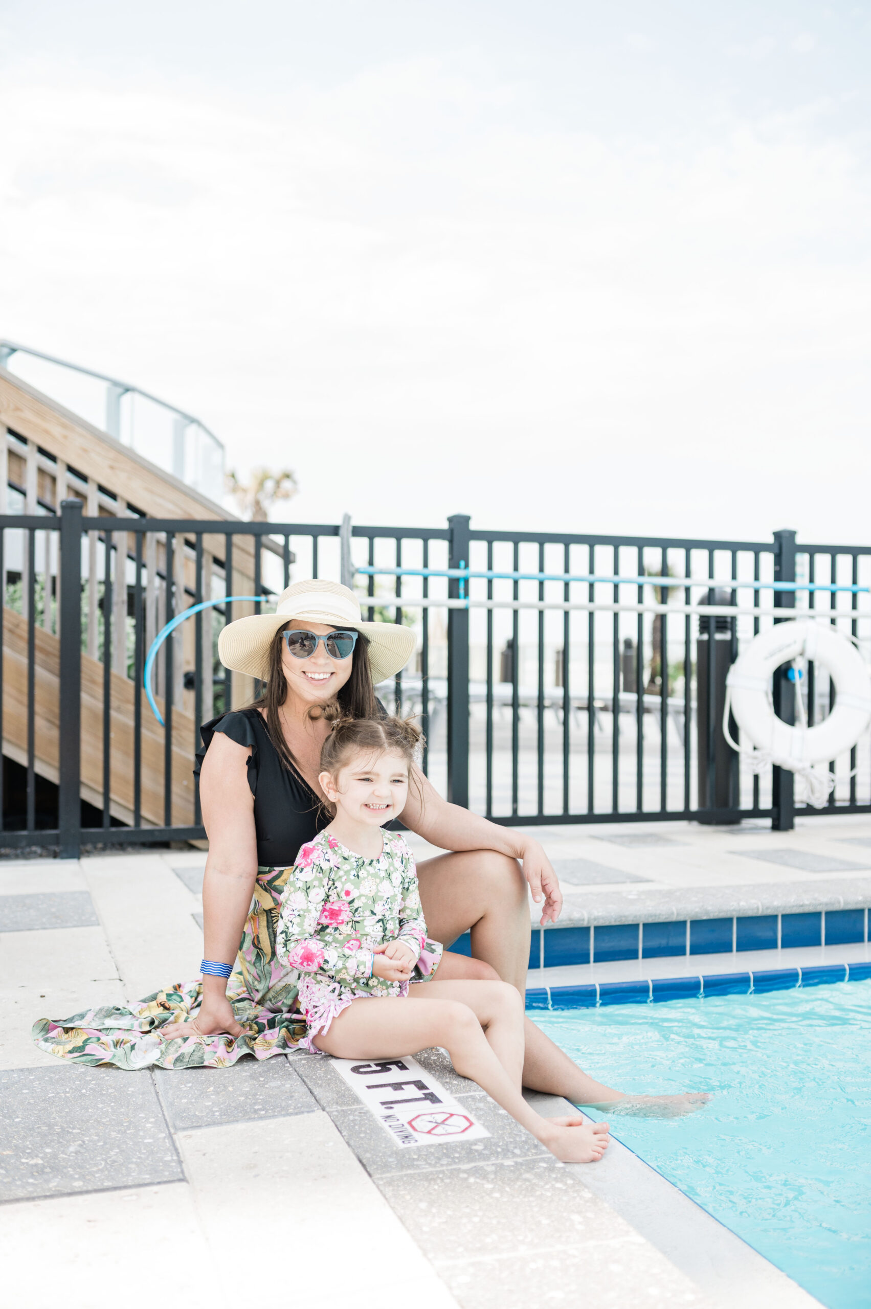 Brittney Naylor and Eleanor sitting on pool deck with their feet in the water at Max Daytona Beach Resort