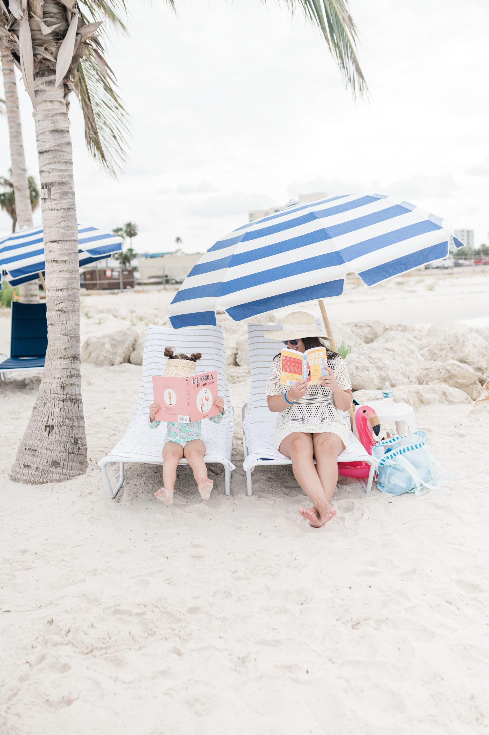 The best beach resort in Clearwater JW Marriott Clearwater Beach. Brittney Naylor and daughter sitting in beach chairs under umbrella reading books. Best Family Resorts in Florida.
