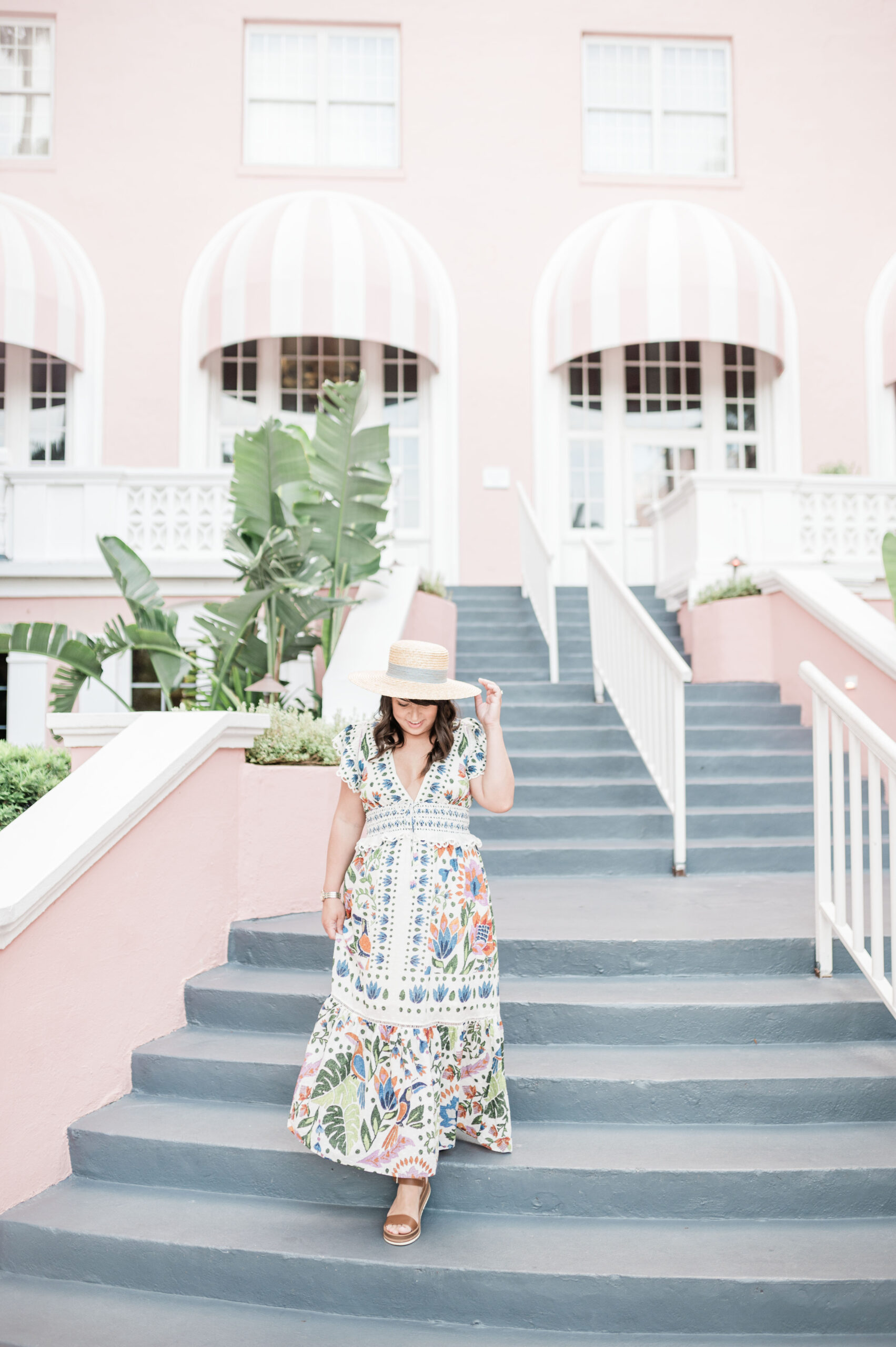 Brittney Naylor wearing Farm Rio maxi dress and hat walking down the stairs at The Don CeSar most instagrammable hotel in Florida