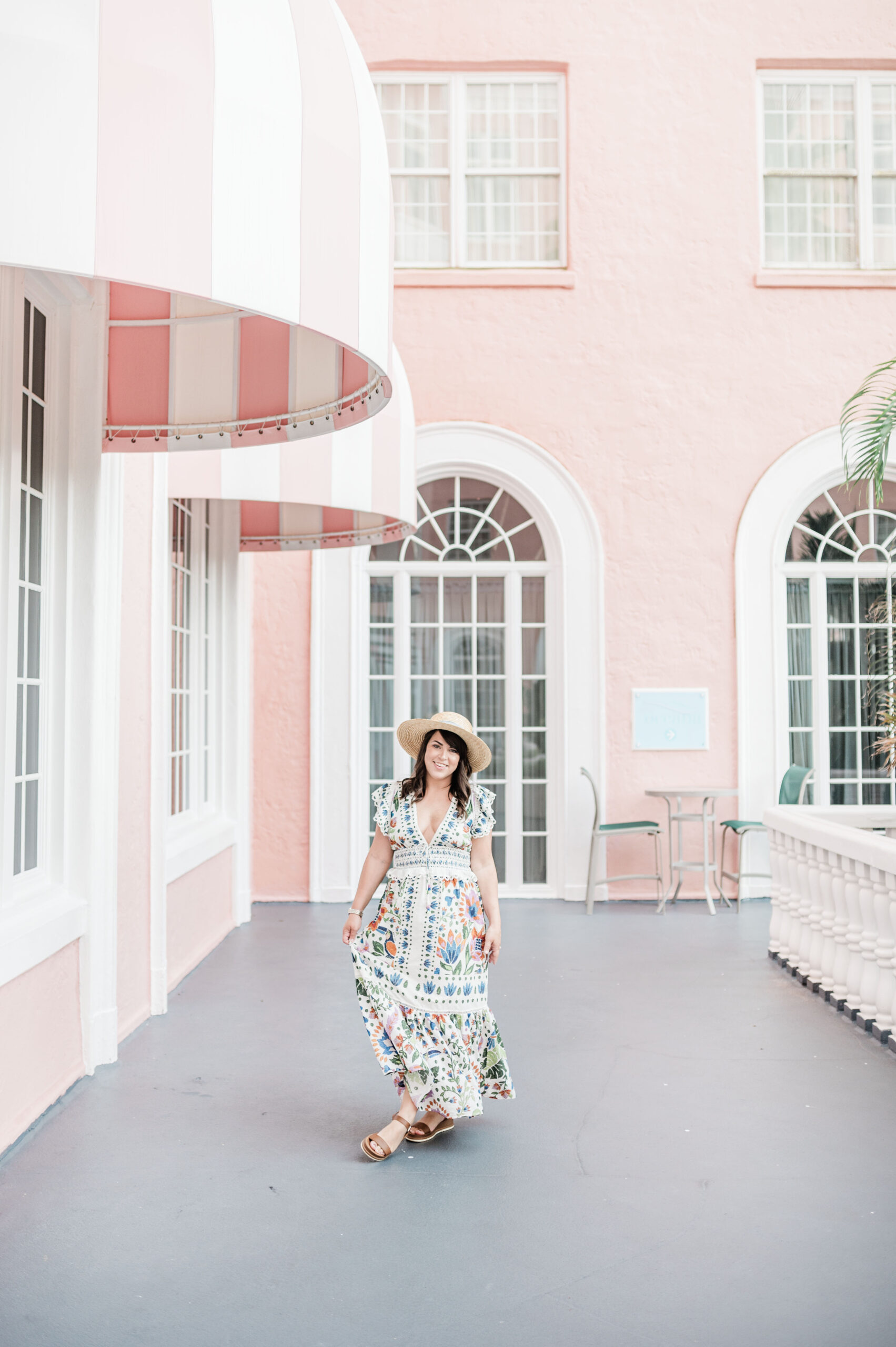 Brittney Naylorwearing Farm Rio maxi dress waving bottom of dress standing under pink and white awnings at the pink palace