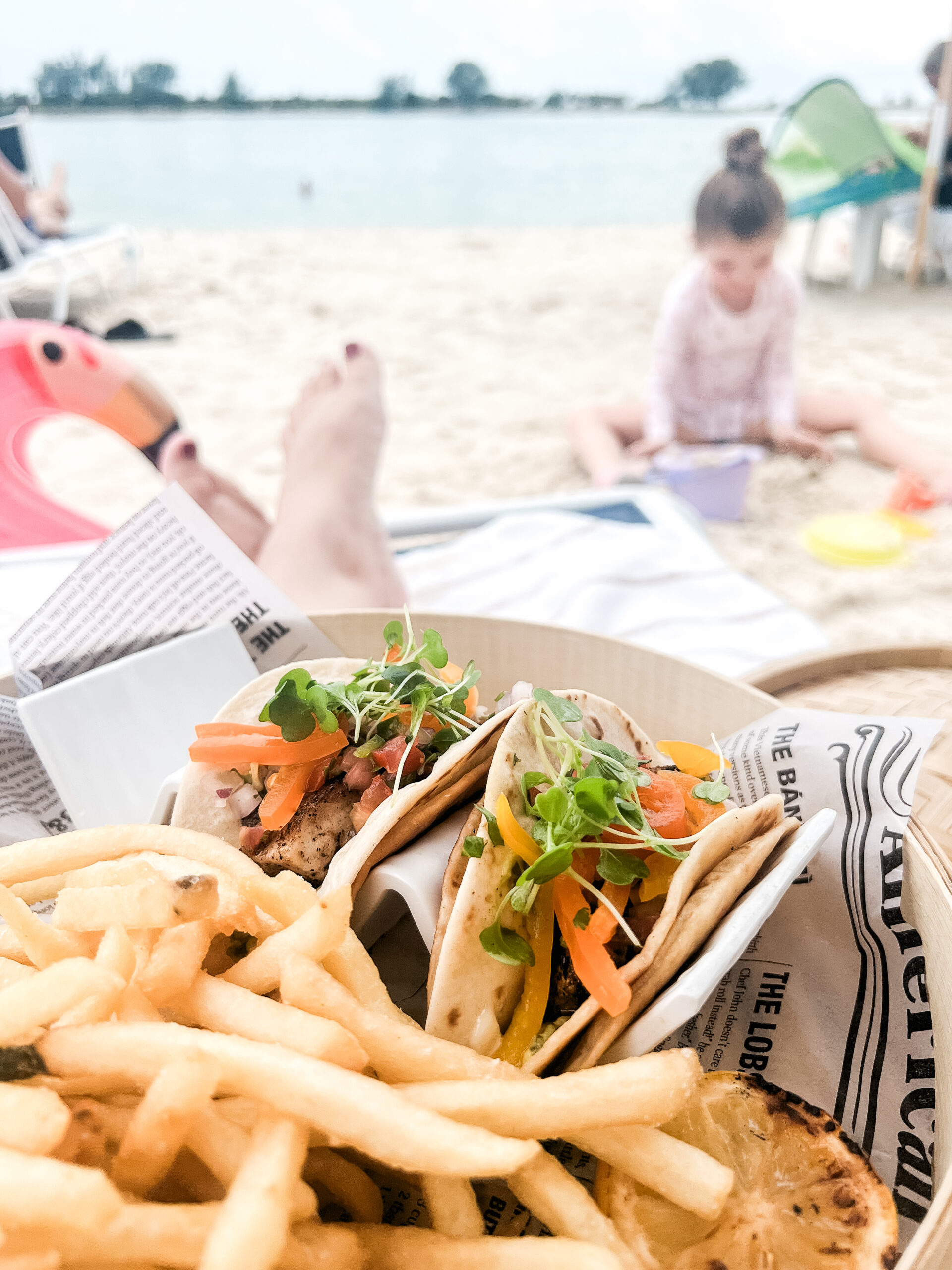 plated meal featuring fish tacos and french fries from Eskape Beach Bar and Grill at JW Marriott Clearwater Beach. Enjoying meal beachside as daughter plays in the sand.