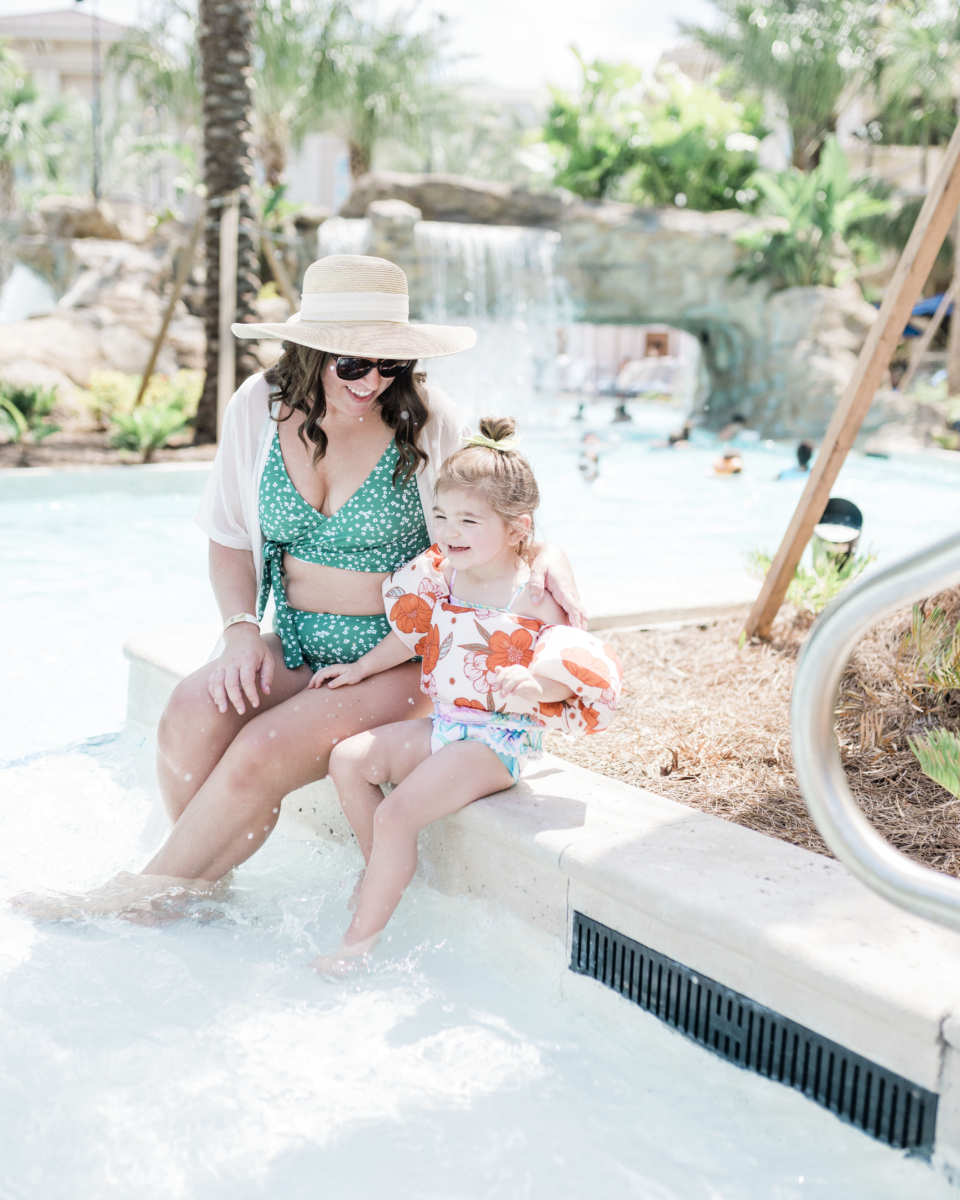 Brittney Naylor and daughter sitting on ledge of lazy river at Gaylord Palms in Kissimmee, Florida. Best Family Resorts in Florida.