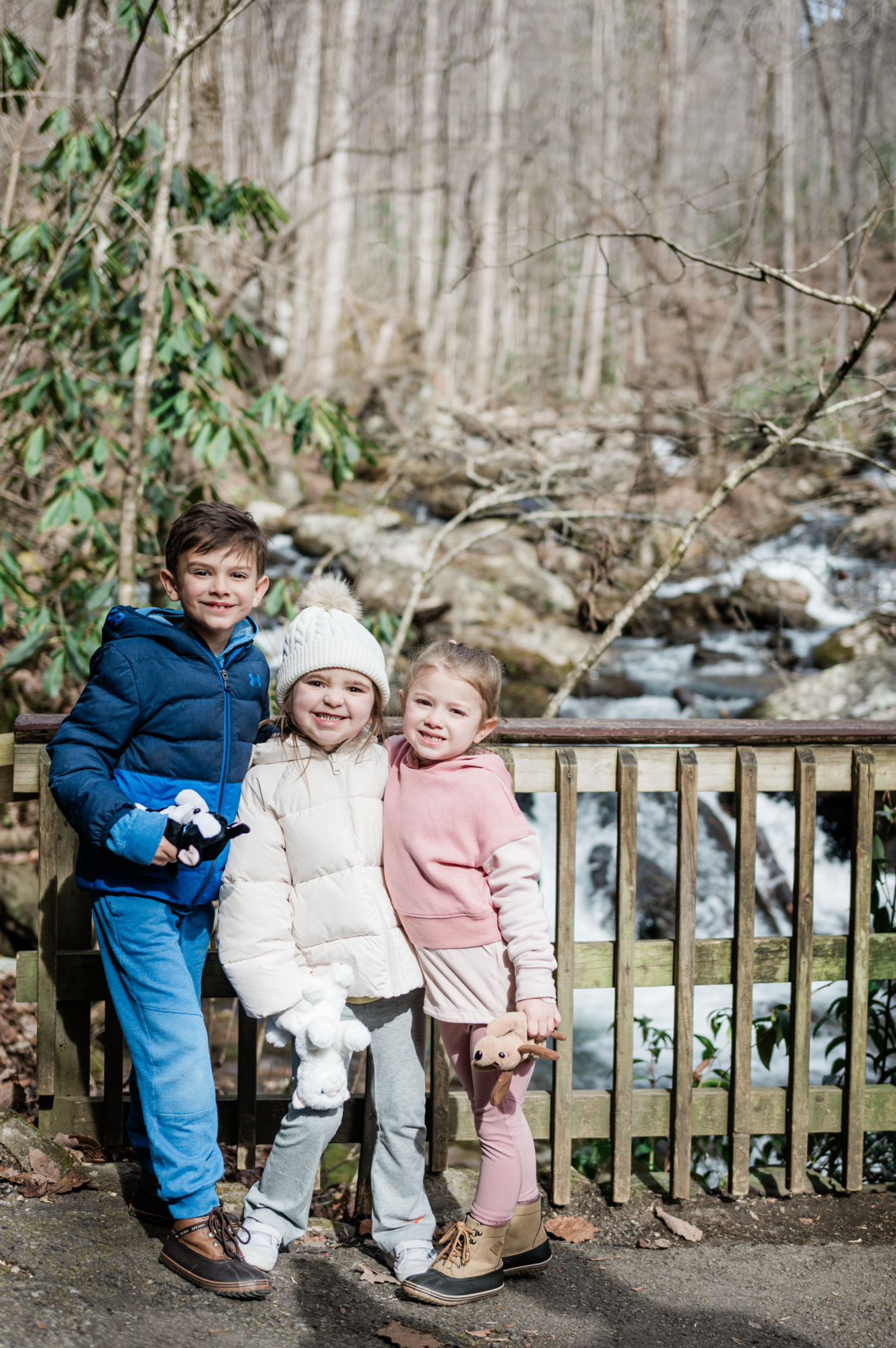 Three kids huddled together in front of creek at Anna Ruby Falls trail