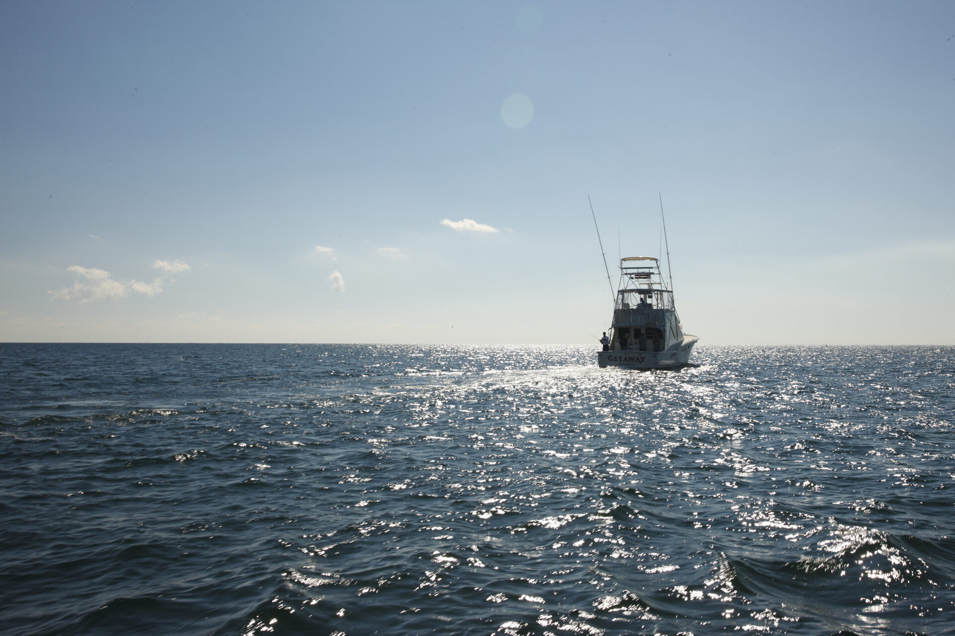 Fishing Charter from Gulf Shores Orange Beach Alabama, fishing boat off in the distance in the water with fisher rods hanging off--photo courtesy of Alabama Beaches Tourism--best gulf shores activities for families