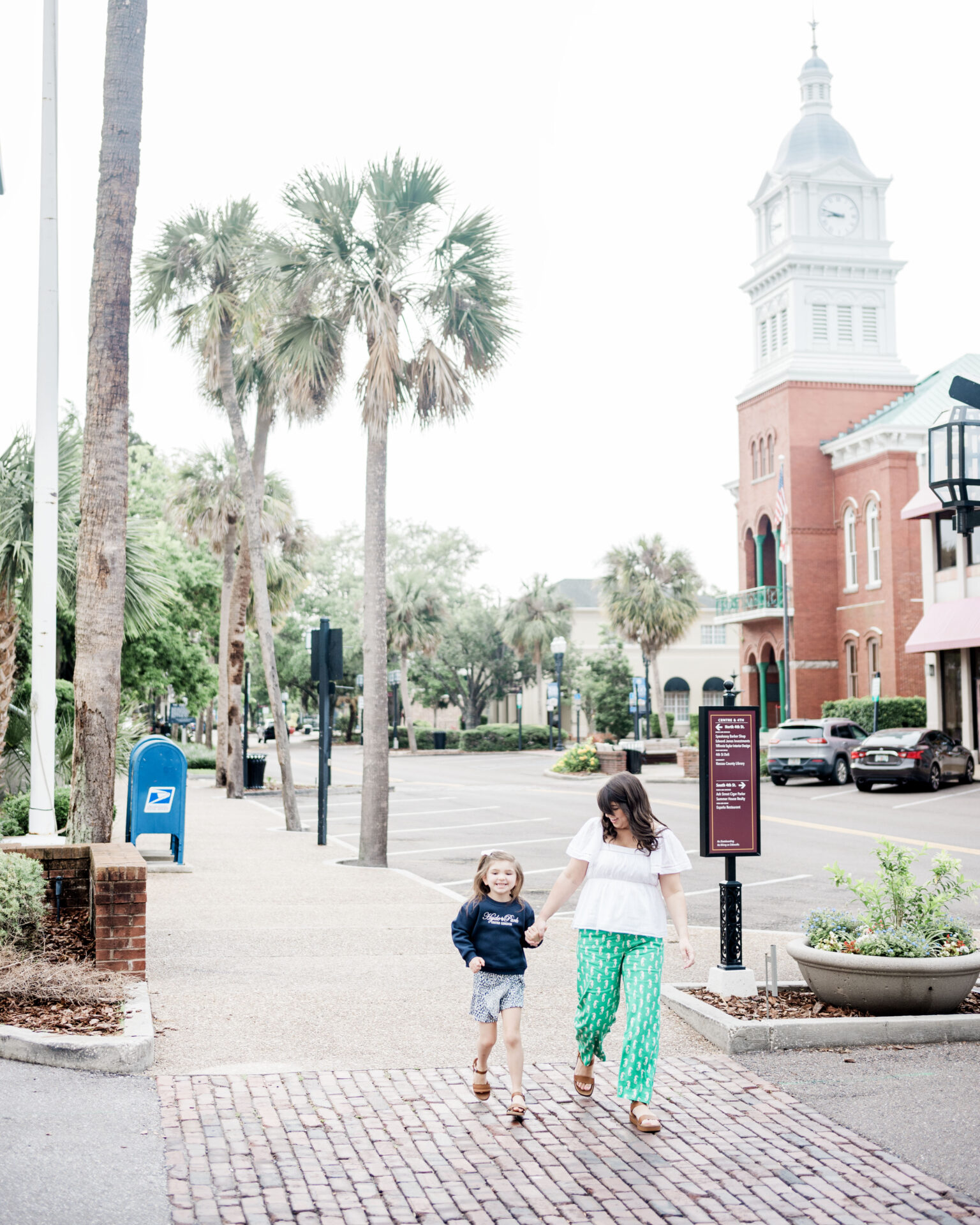 a woman and child walking on a sidewalk, downtown Fernandina Beach, weekend in Fernandina Beach