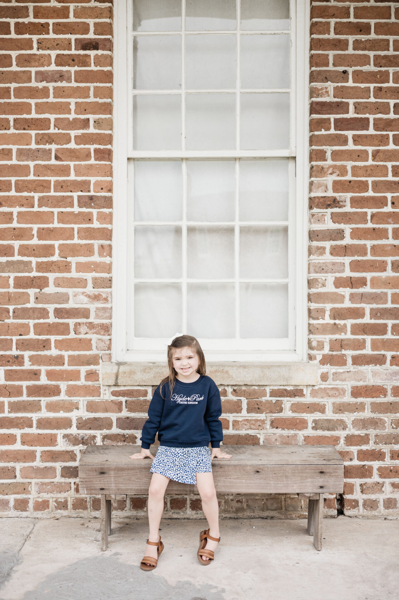 a girl sitting on a bench in front of a brick building at Fort Clinch State Park in Amelia Island