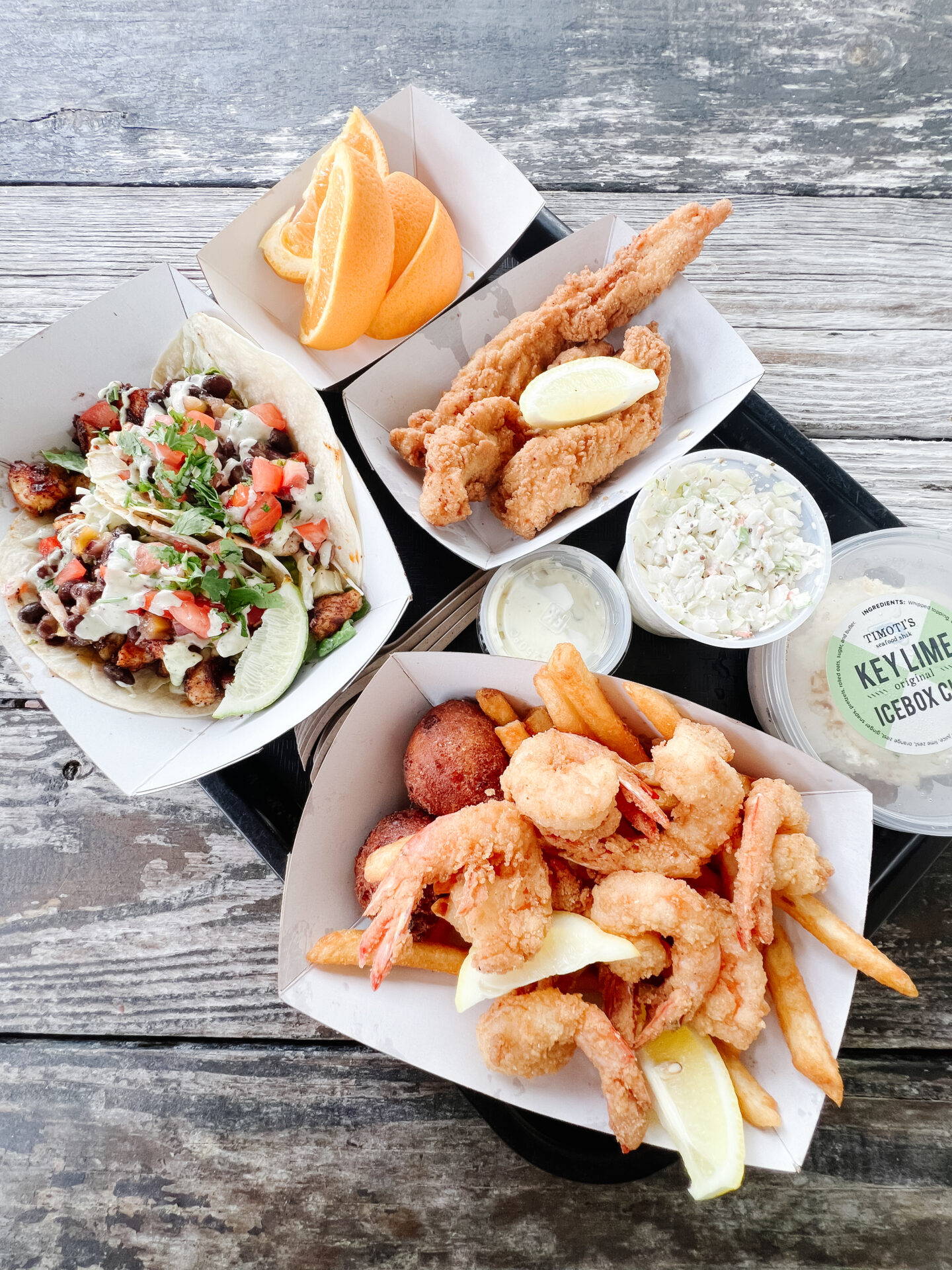 a tray of food on a table featuring fried shrimp, fish tacos, chicken tenders from Timoti's in Amelia Island