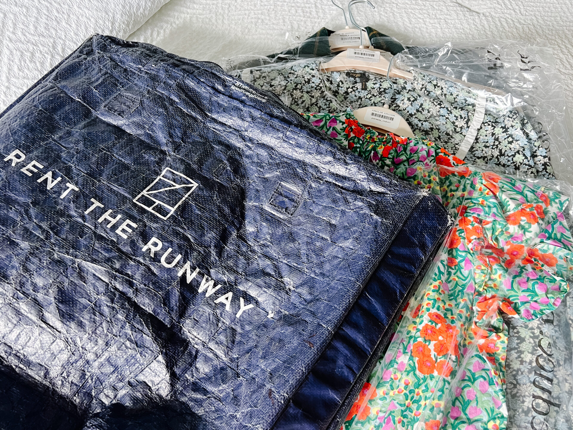 Nuuly vs Rent the Runway, image showing how Rent the Runway delivers their monthly rentals in a plastic tote, clothes are on hangers and in plastic garment bag