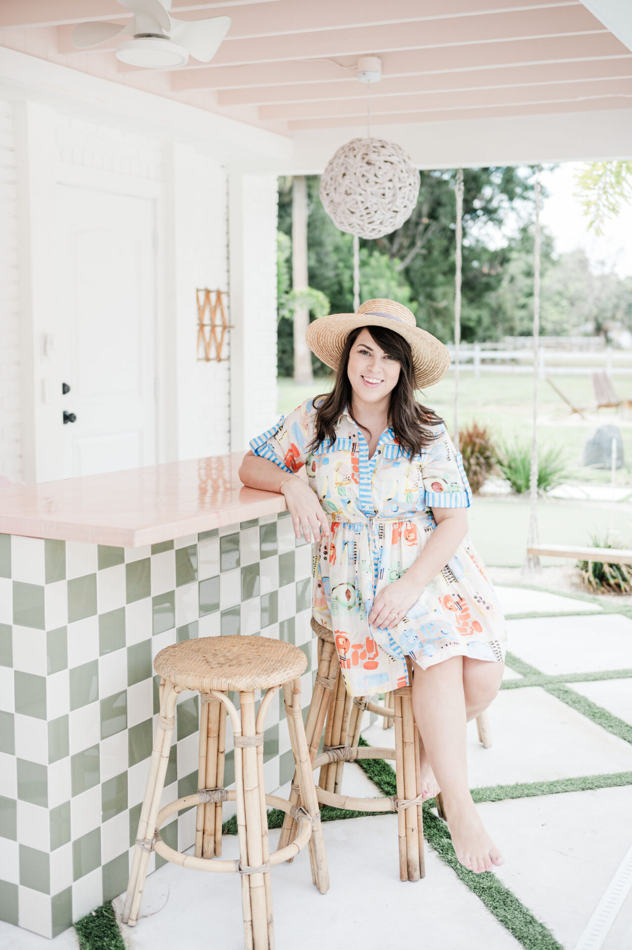 Brittney sitting at outdoor bar at airbnb in Vero Beach wearing dress rented from Rent the Runway