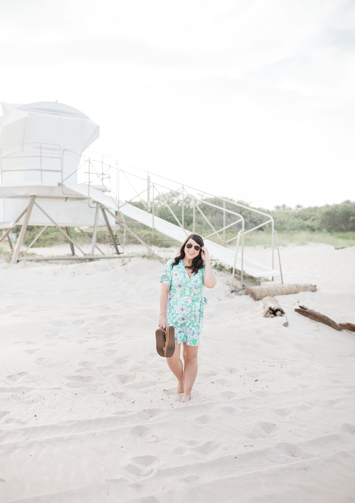 Brittney standing in the sand in front of a lifeguard stand in Vero Beach wearing Lilly Pulitzer rented from Nuuly